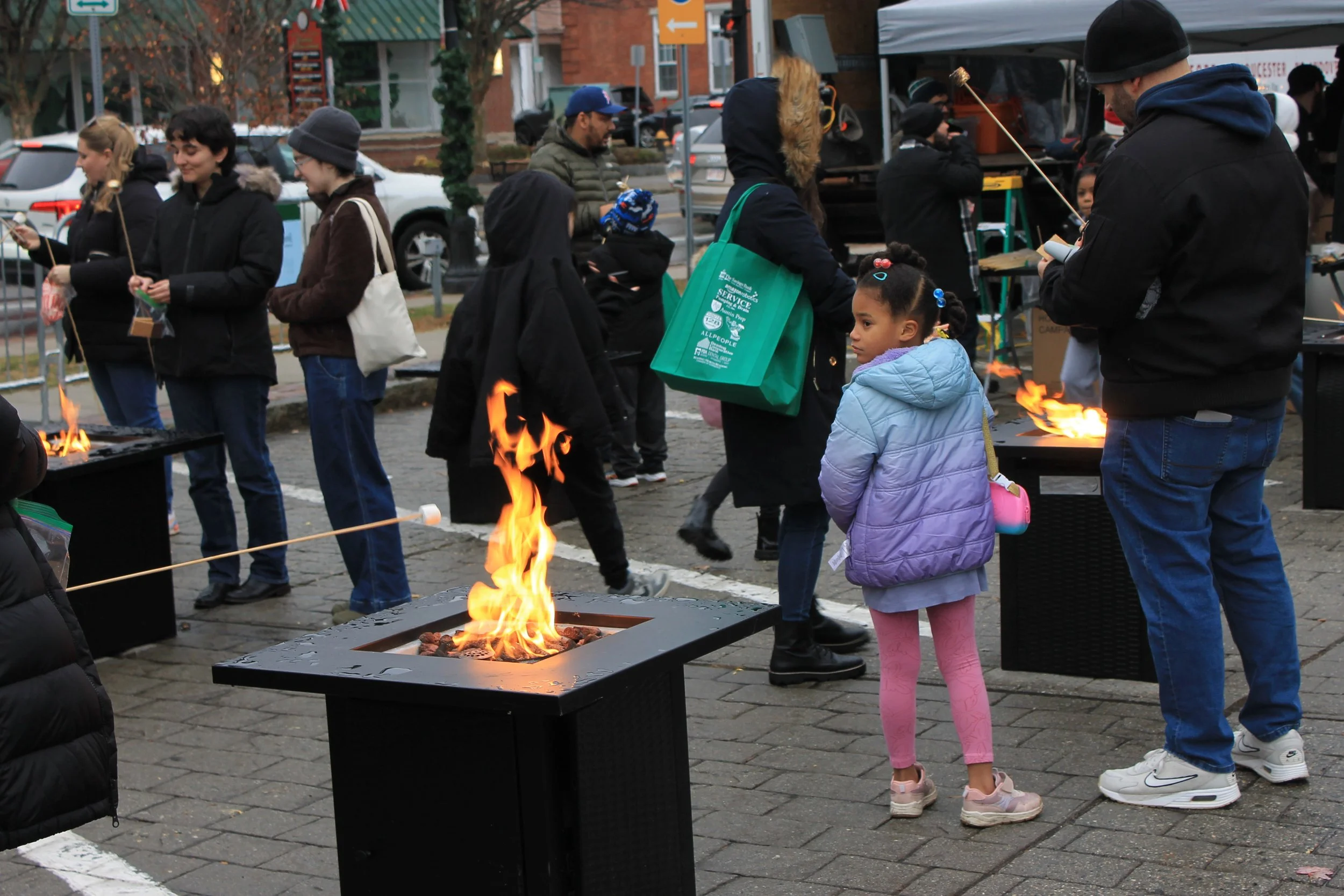 Families roasting marshmallows for s'mores at the fire pits at the Tree Lighting Ceremony on the Town Common.