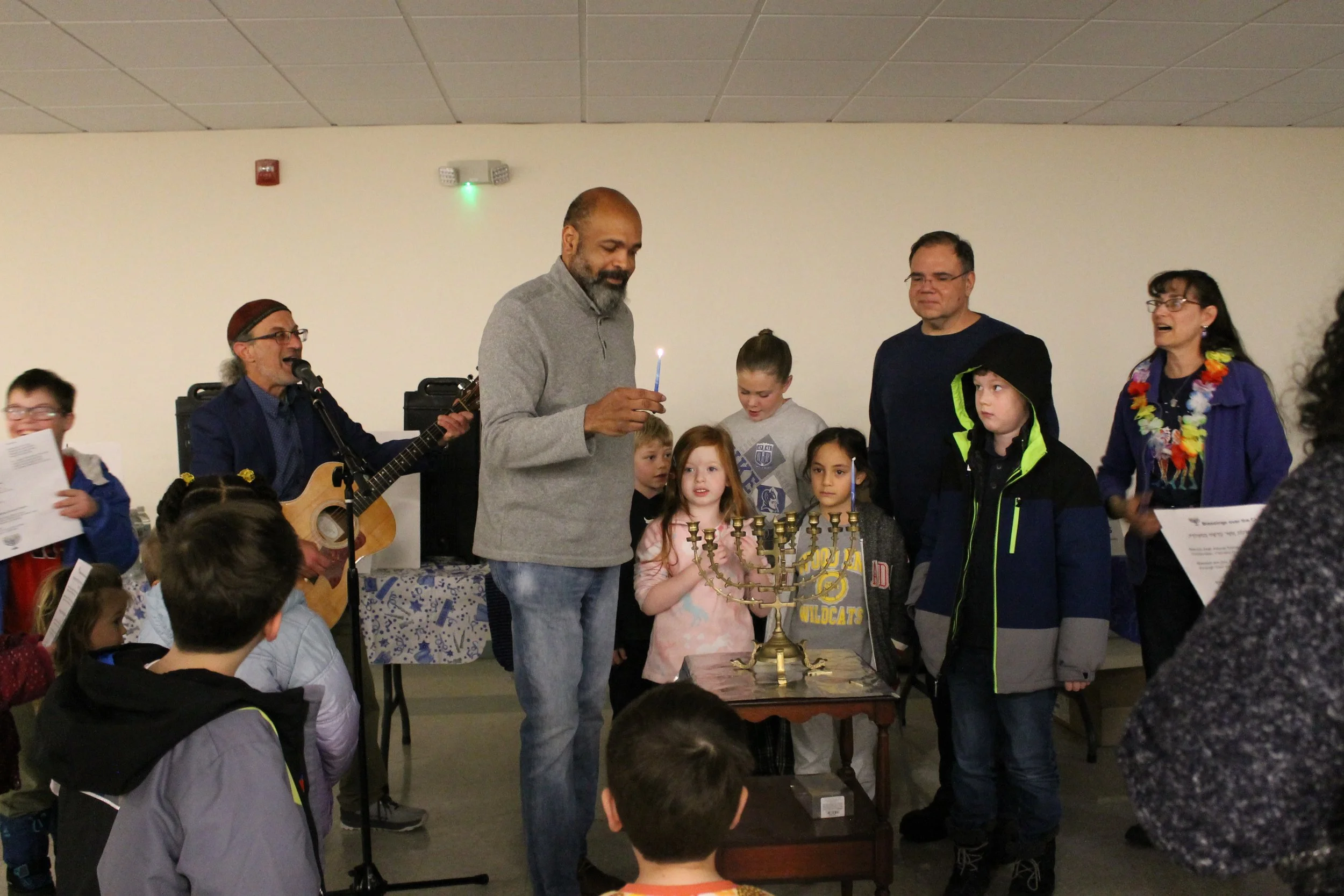 Rabbi Micah, Director of OESJ Albert Pless, Town Manager Matt Kraunelis, and organizer Anne Schwartz surrounded by children during the program at the Menorah Lighting.