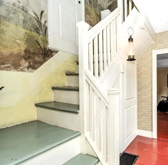 Historic staircase at 52 Salem Street featuring a rare mural believed to be in the style of Rufus Porter, showcasing early American folk art within the home.