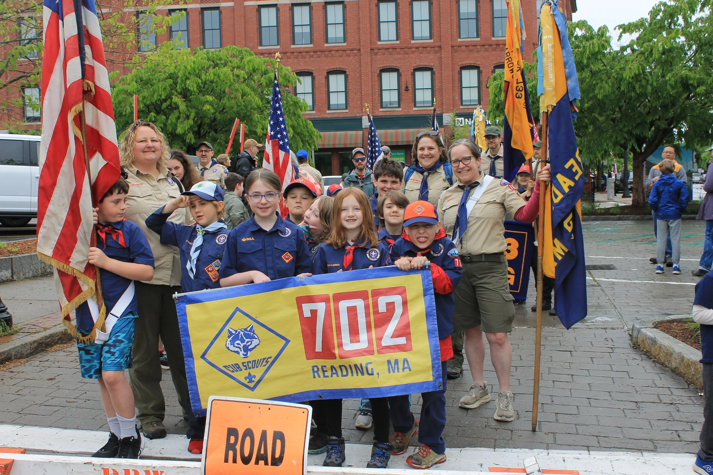 Scout Pack 702 lines up with flags and banners ahead of the parade.