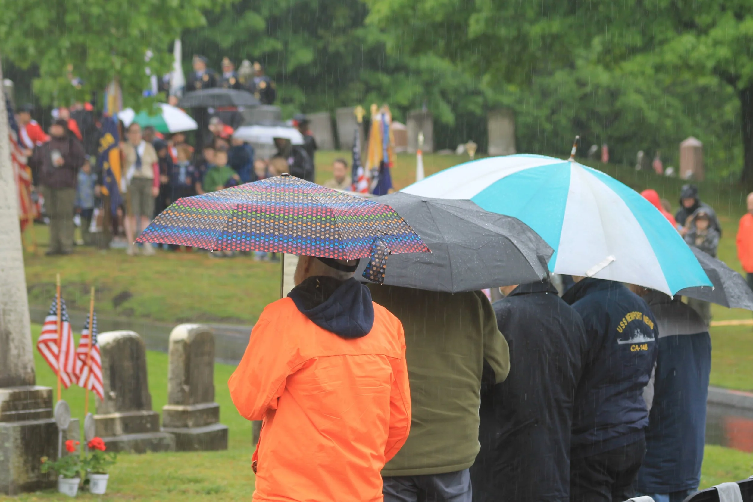 Residents huddle under umbrellas as rain falls steadily during the Laurel Hill ceremony.