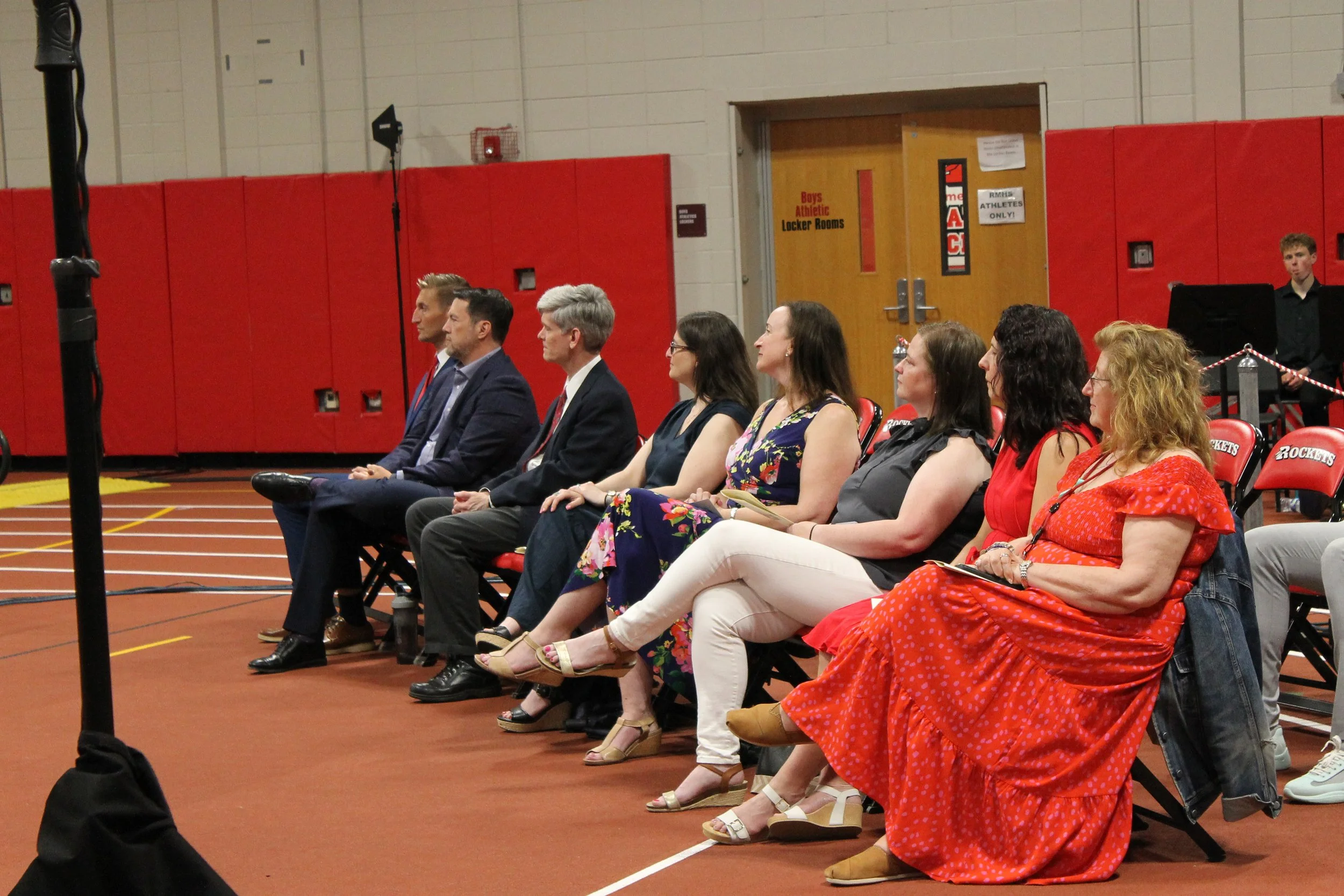 School and district administrators, School Committee members, and staff look on from their seats along the sideline during the ceremony.