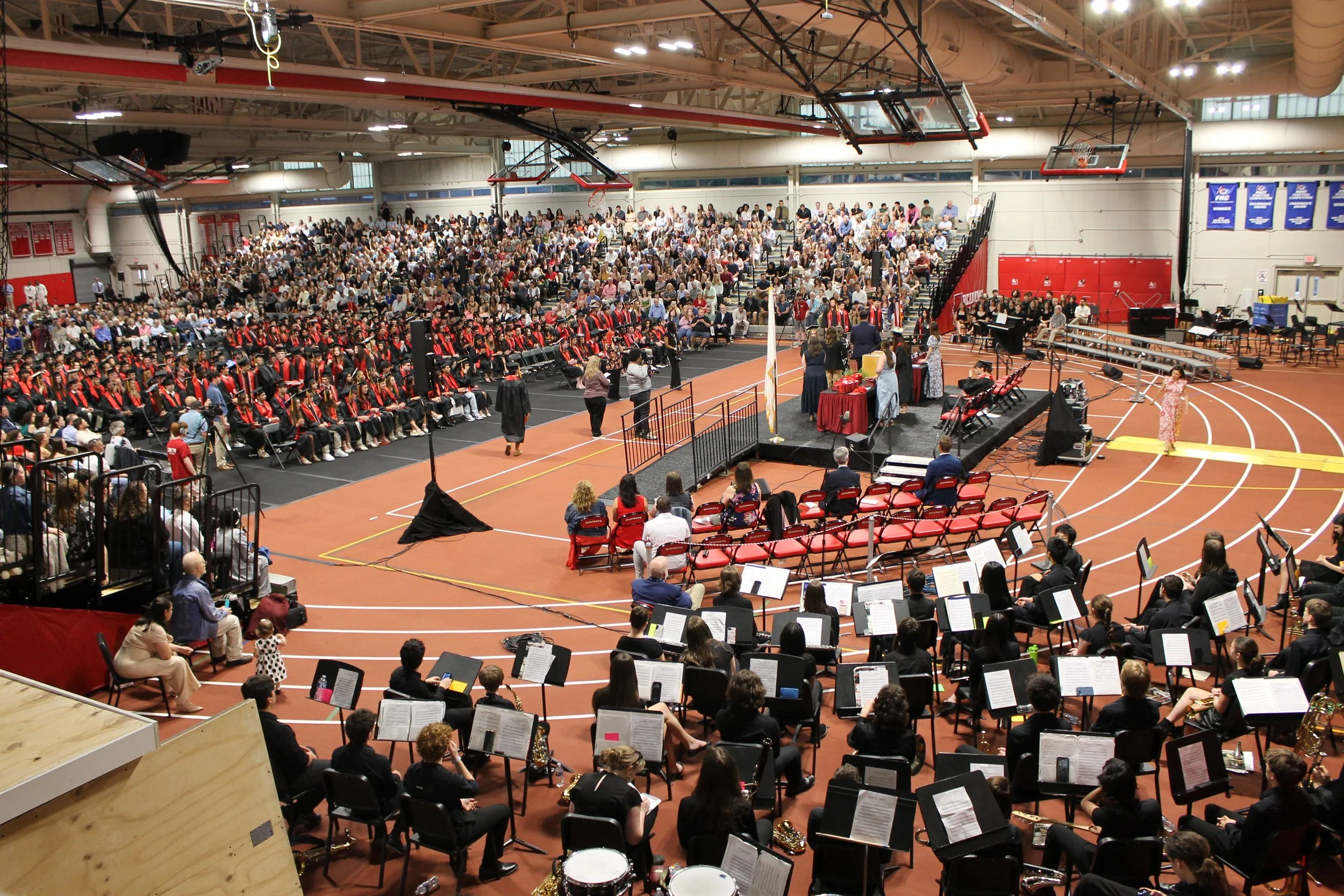 An overhead view of the Fieldhouse captures the full scale of the ceremony, with the RMHS Band in the foreground, graduates on the floor, and a packed house of spectators in the stands.
