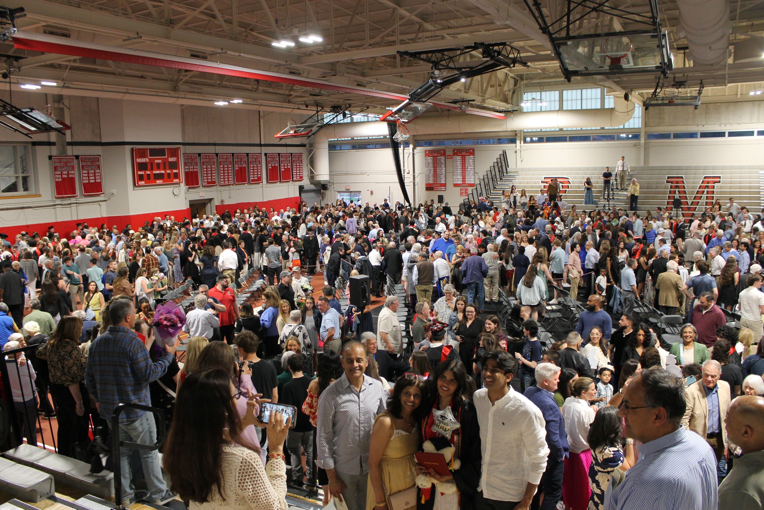 Graduates and families fill the floor of the Fieldhouse following the ceremony, celebrating and taking photos together.