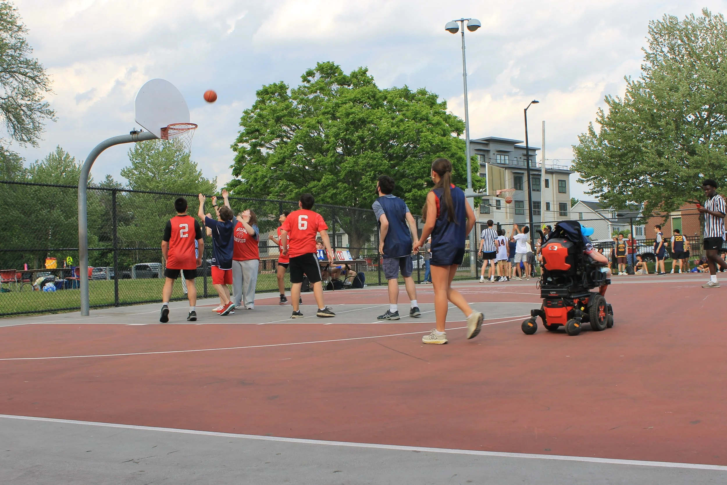 Reading Unified athletes track a shot toward the hoop during outdoor play.