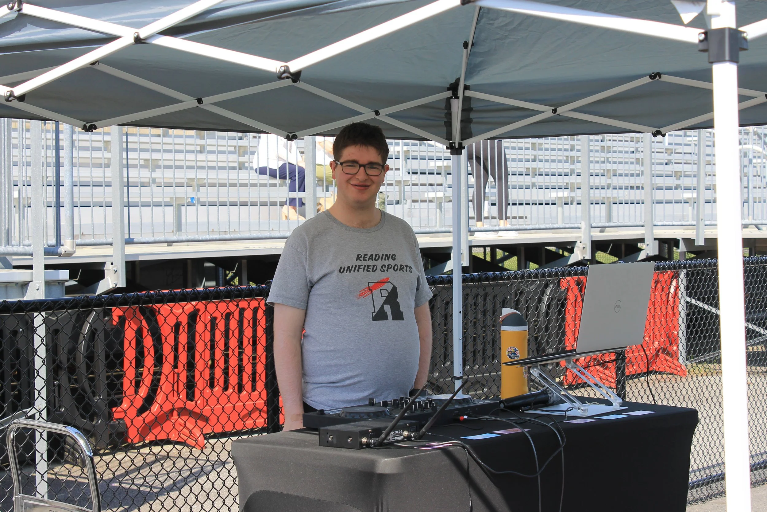DJ Jazzy Jacob stands ready at his table under a tent, set to keep the crowd energized.