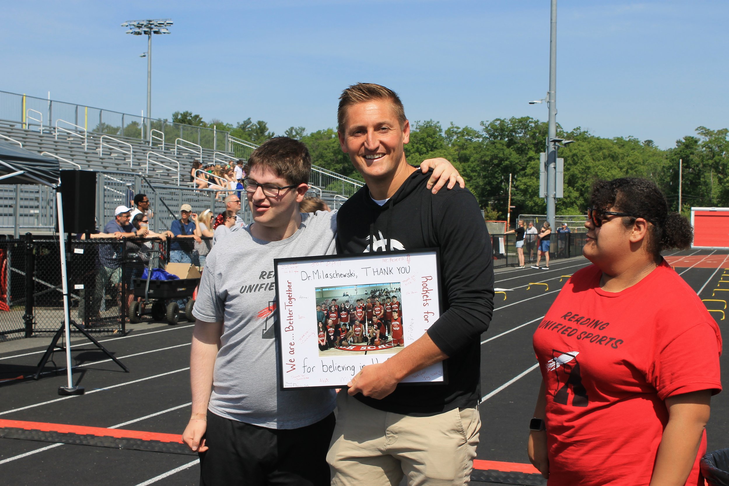 Supt. Milaschewski (center) poses with athletes Jacob Goldlust (left) and Lani McGrady (right) with the framed thank-you gift.