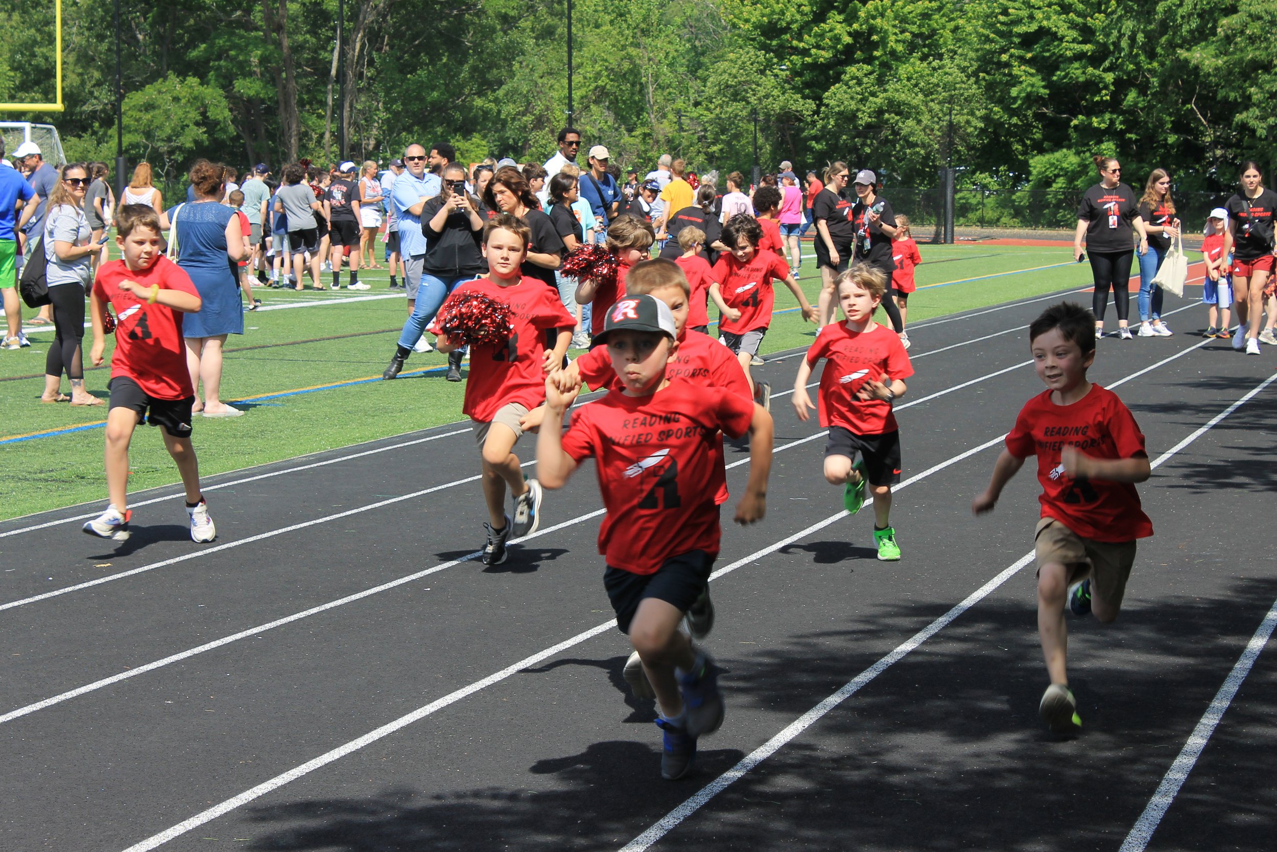 A group of young athletes sprint down the track at Unified Sports Day.