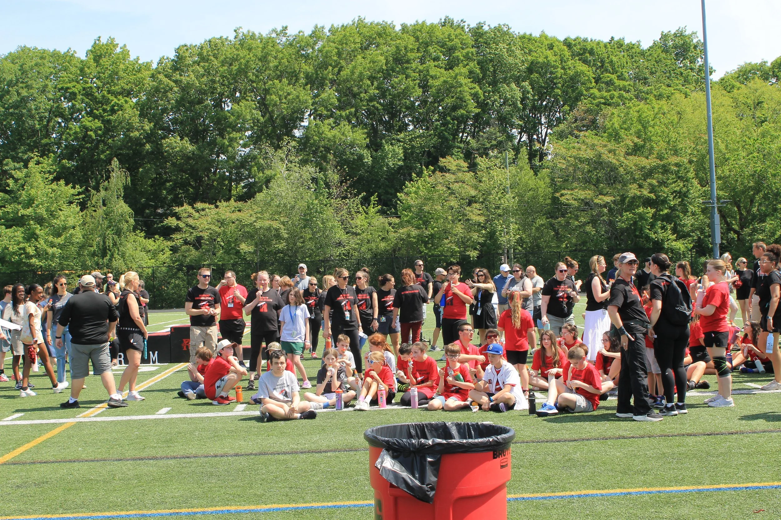 Athletes and volunteers relax on the field, enjoying popsicles after a day of competition.