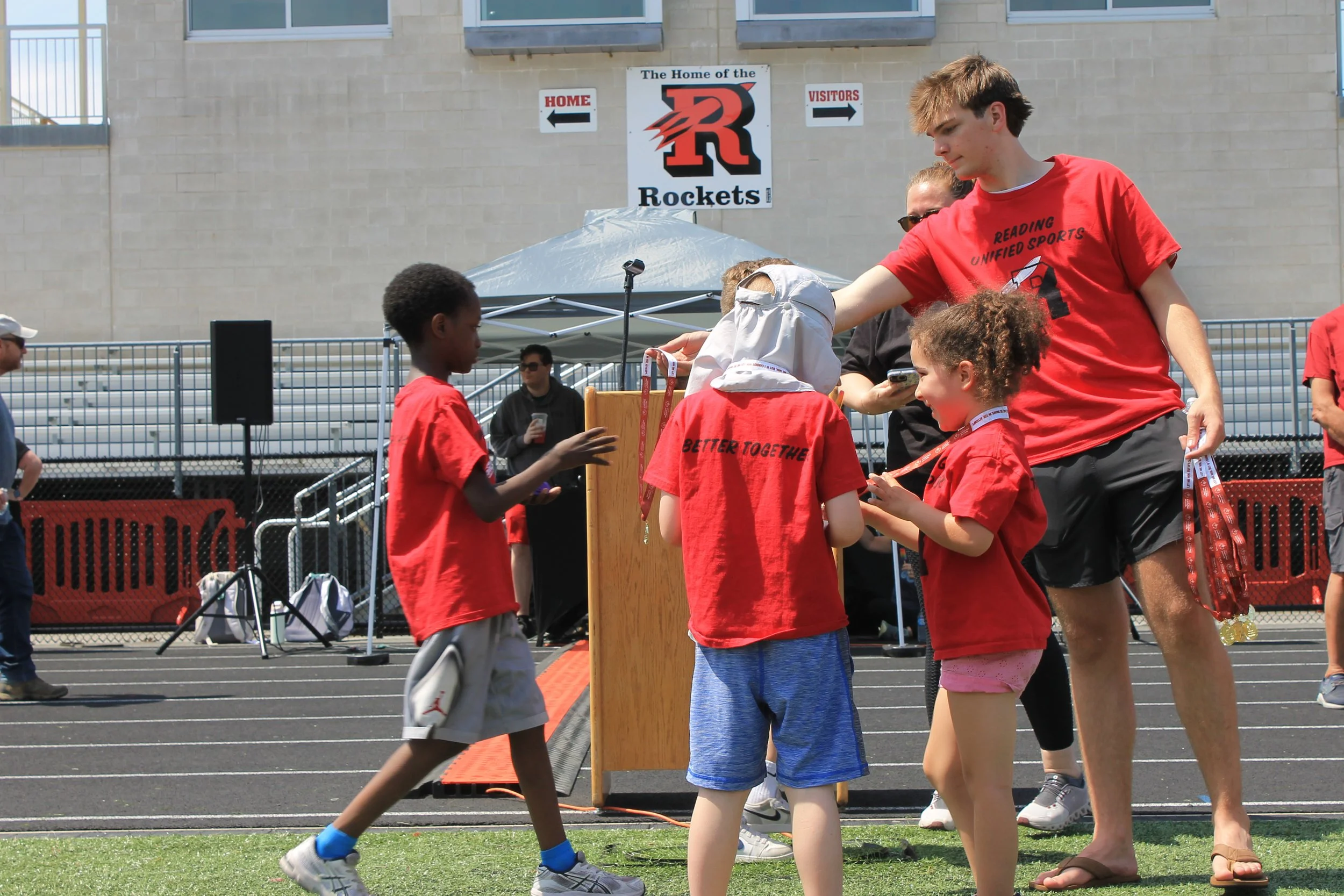 Volunteers from RMHS help younger participants put on their medals after the day's events.