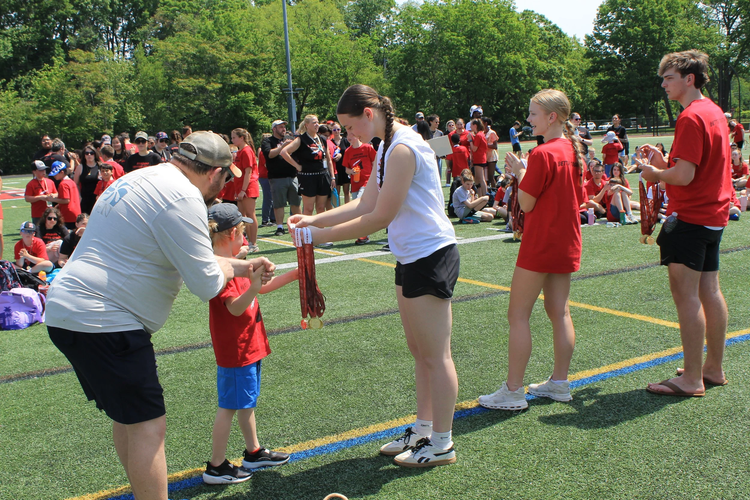 A young athlete received his medal from teammates with his coach by his side.