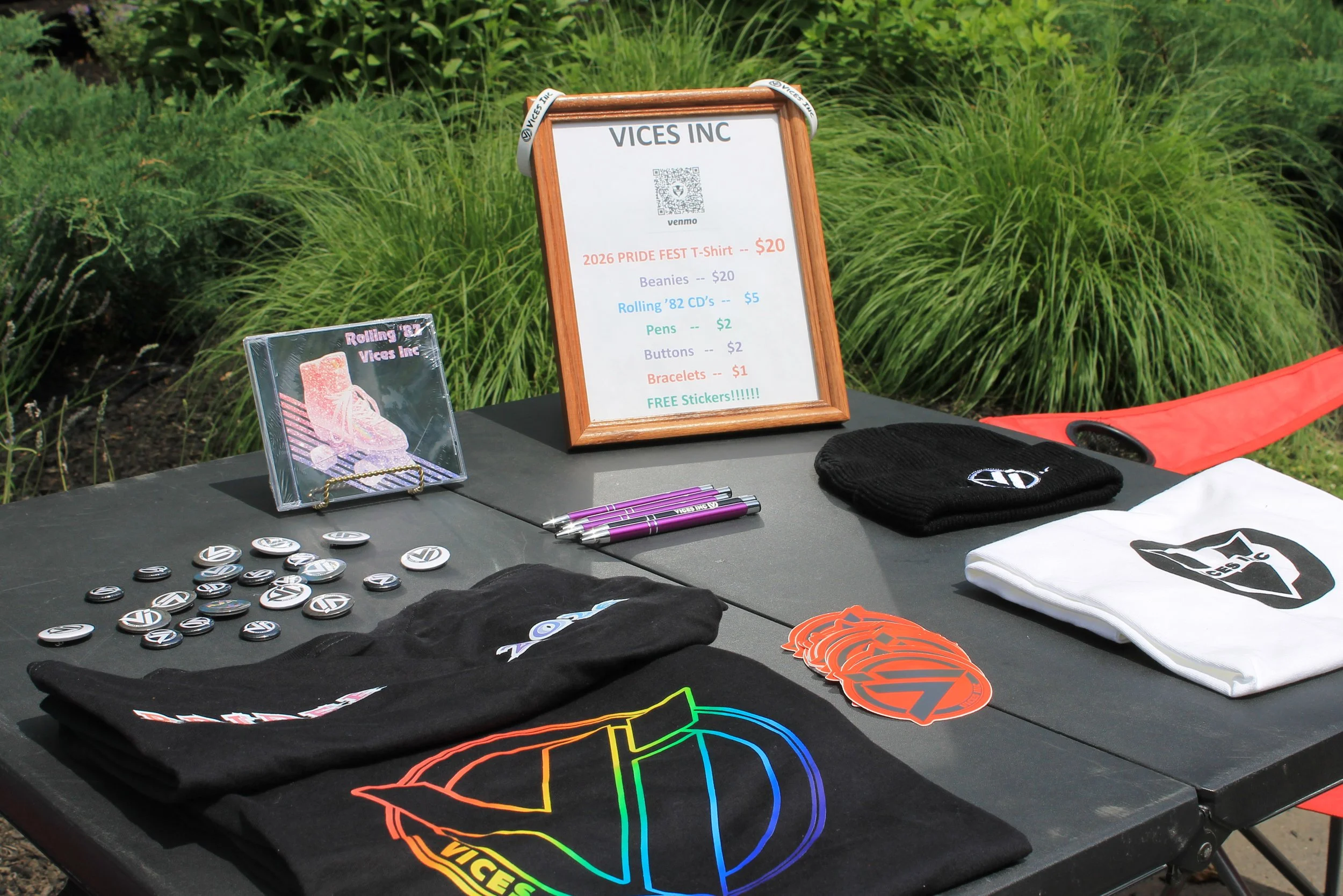 Vices Inc. merch table, featuring their CD, band gear, and stickers.