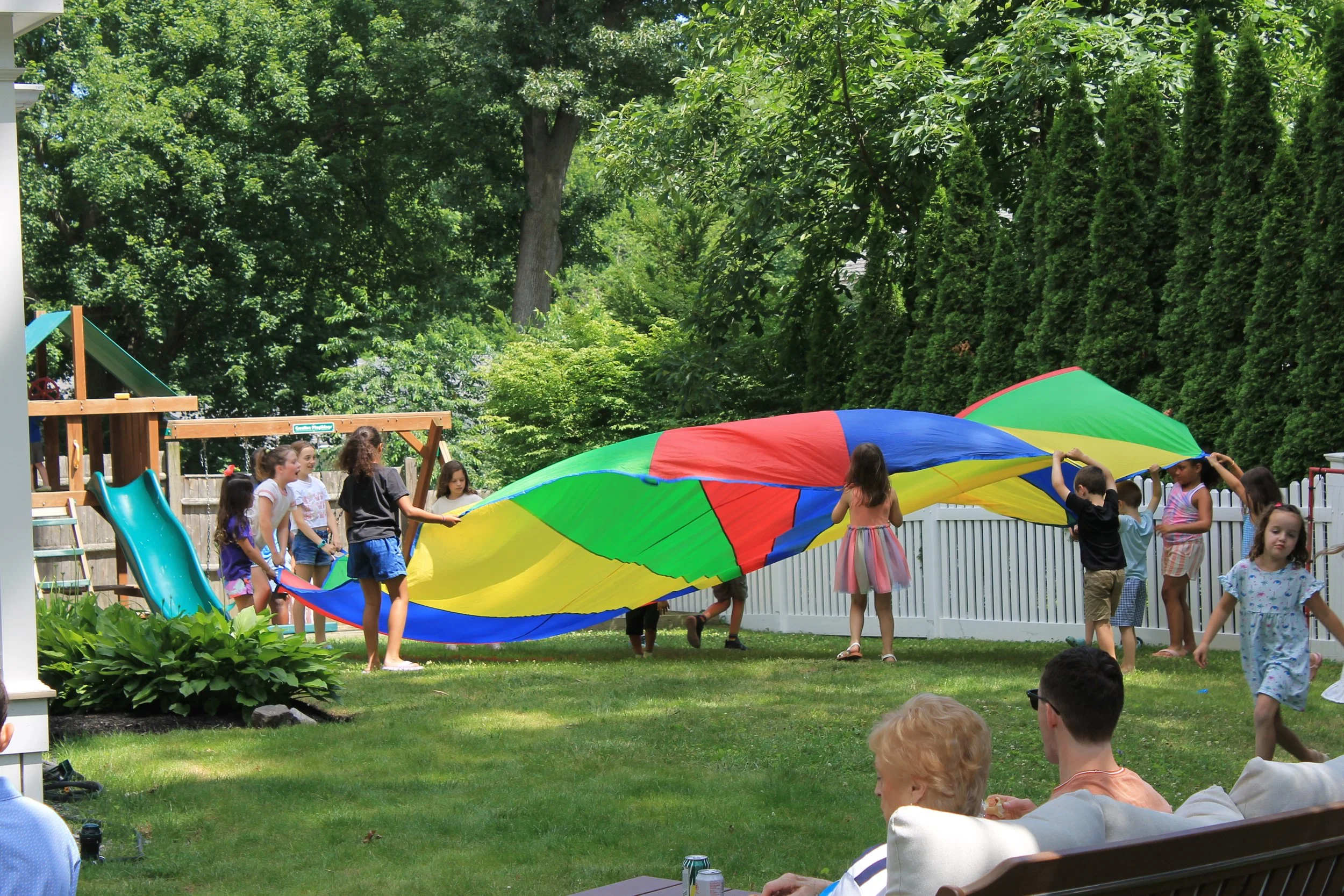 Kids enjoy playing with a parachute in the background at 134 Pine Ridge Road.