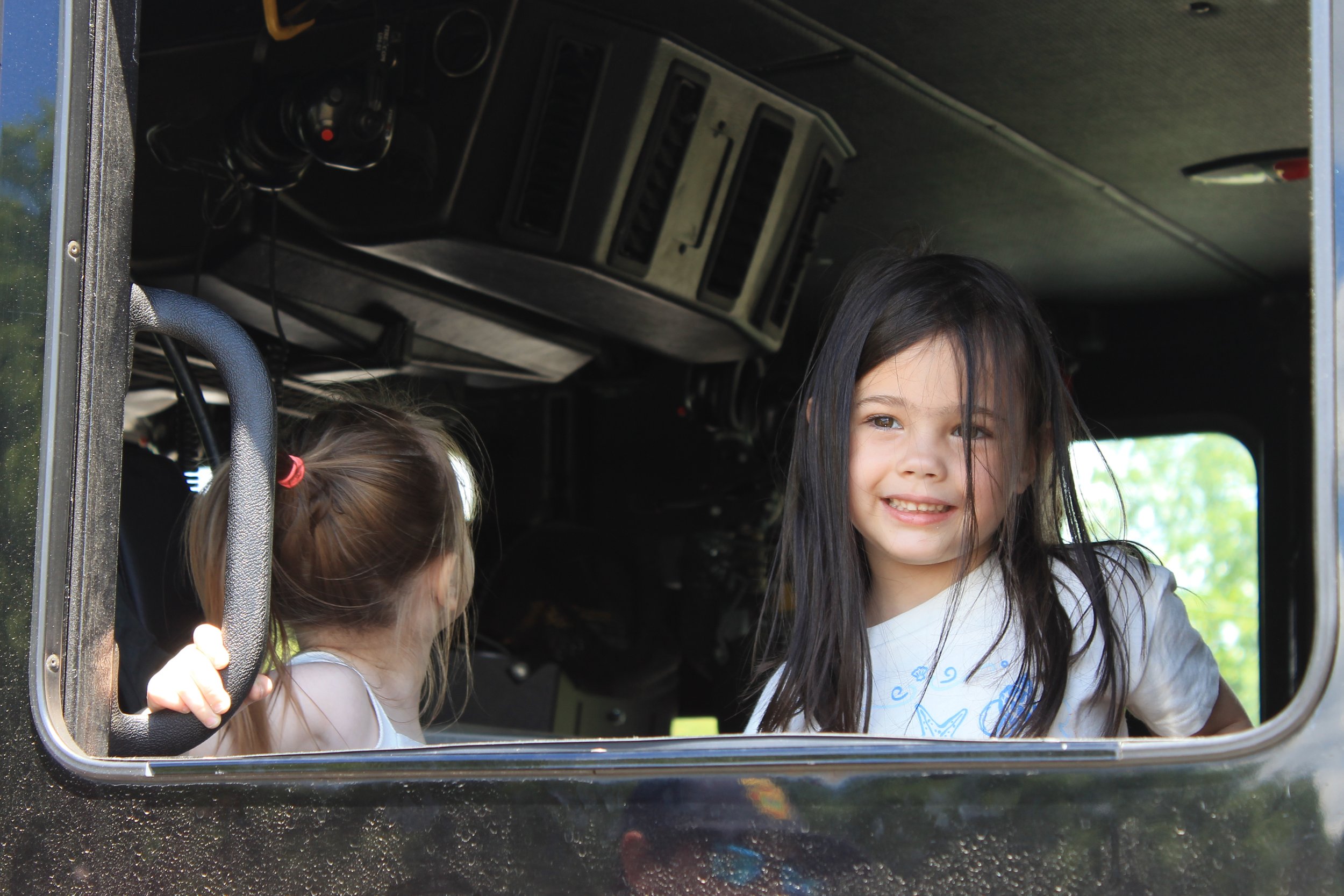 Two young visitors sit in the back seat of a Reading Fire Department vehicle.