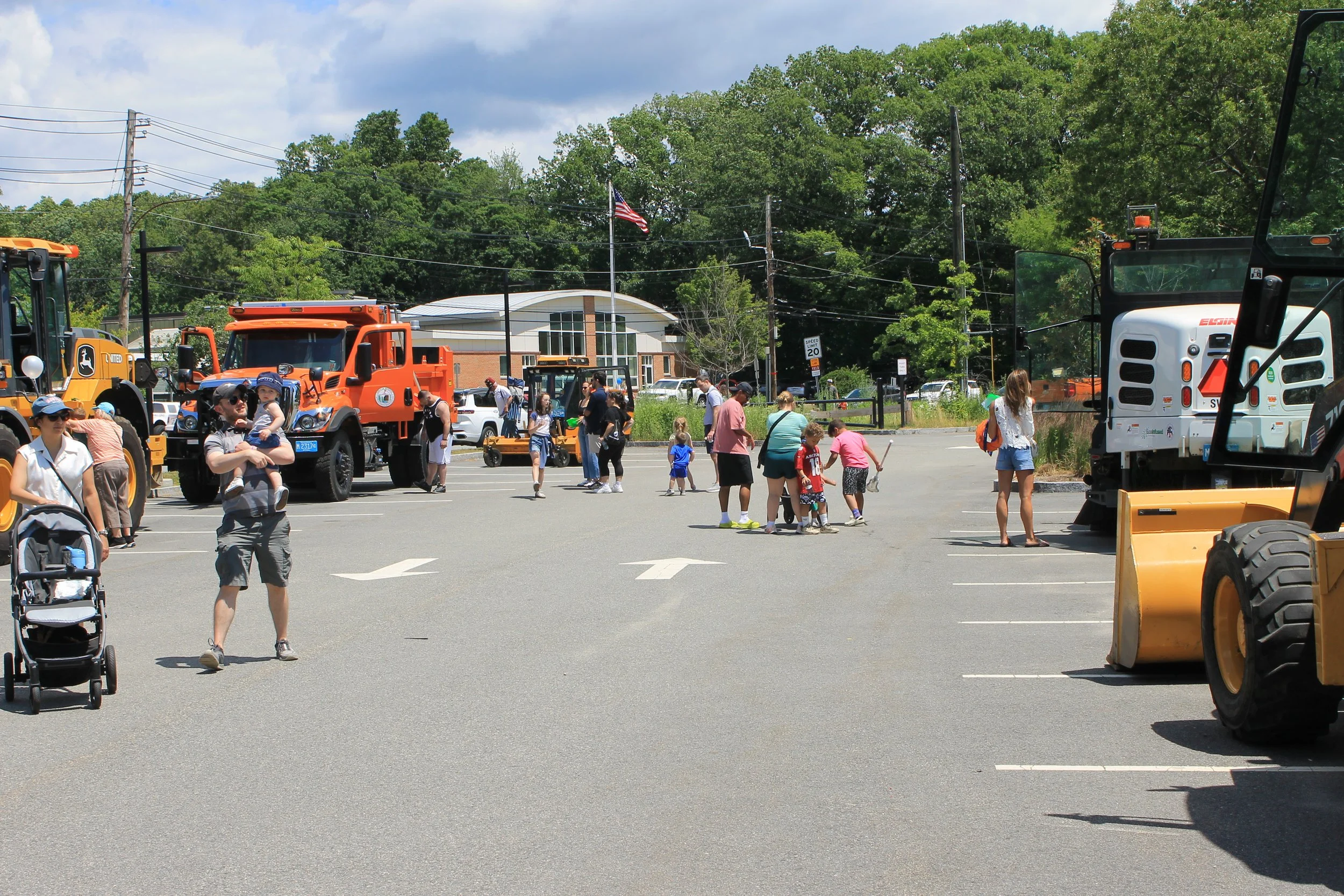 Families explore DPW trucks and heavy equipment lined up in the lot.