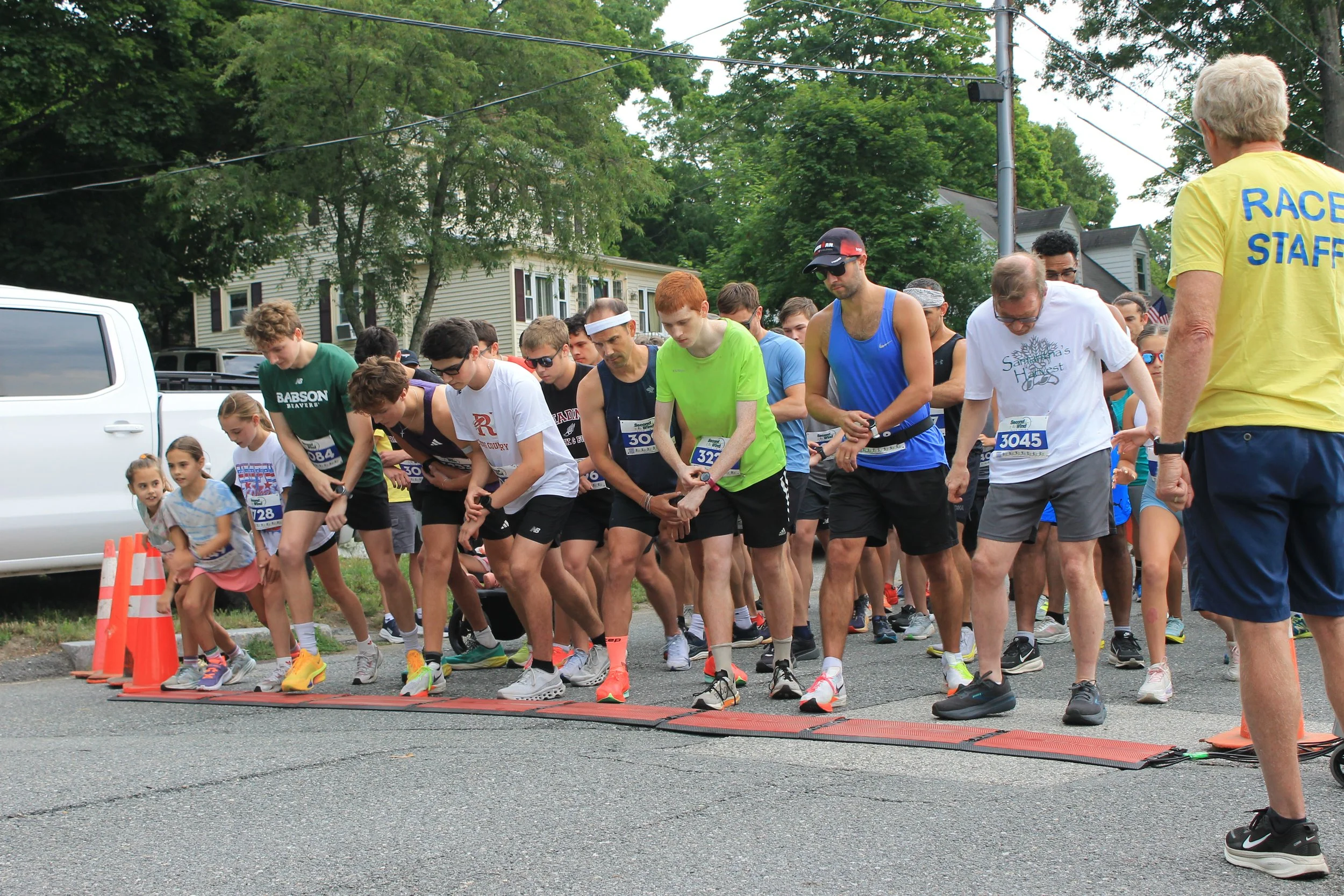 Runners crowd the starting line on Harrison Street, watches ready, as a race volunteer sends them off.