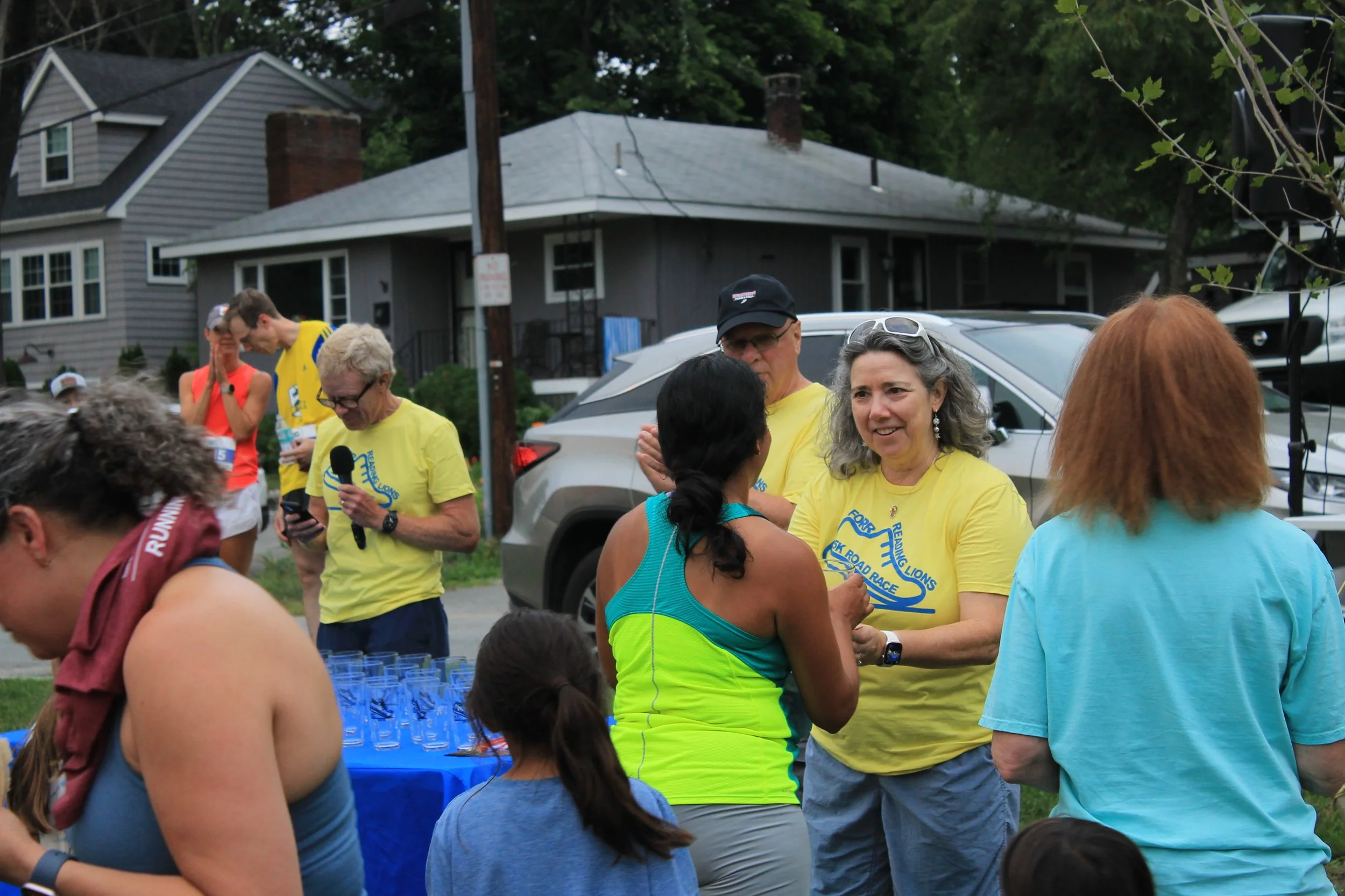 Reading Lions Club President Desirée Zicko presents awards to finishers, with the engraved pint glasses lined up on the table.