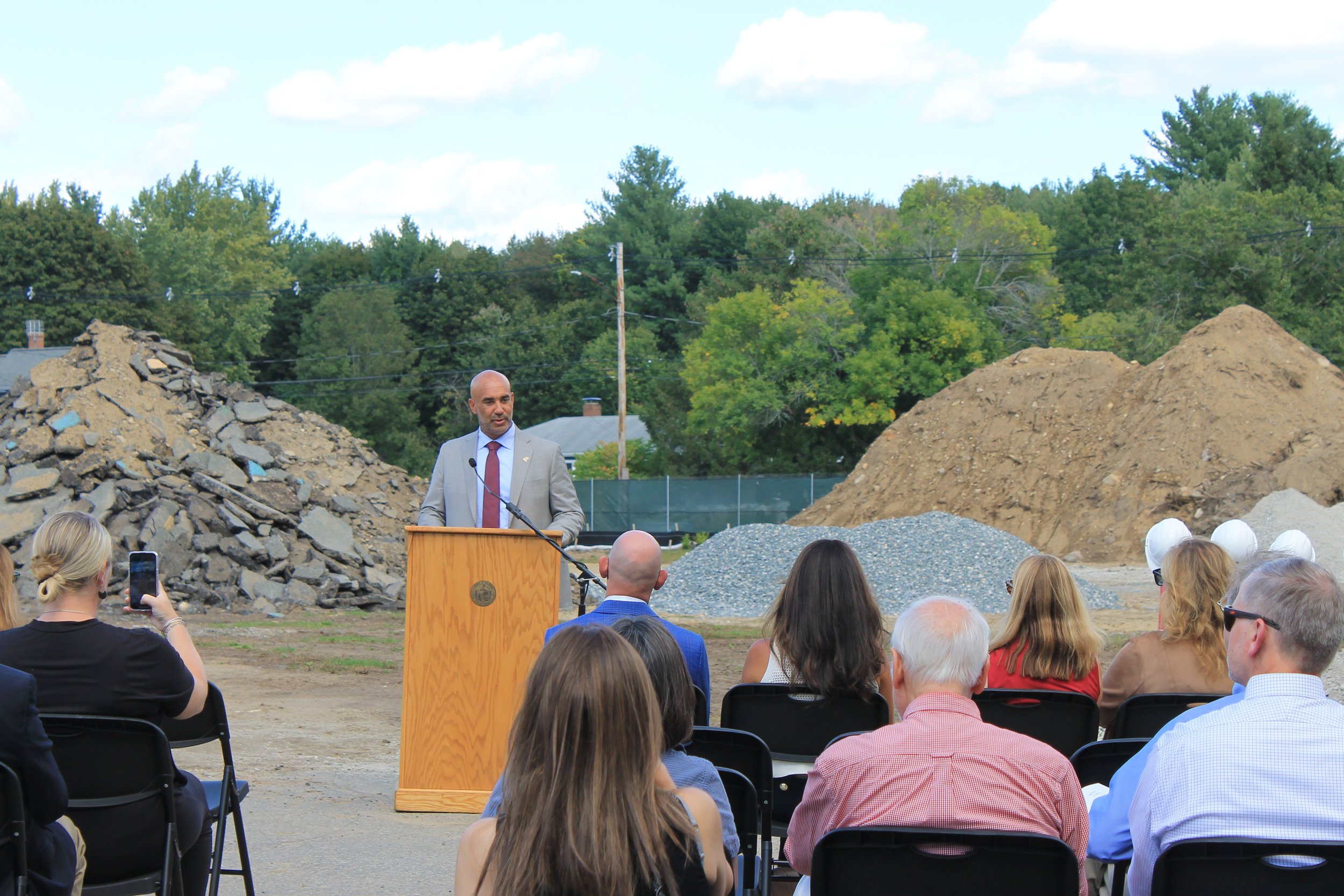 Dr. Henry Turner addresses the crowd at the Killam School groundbreaking, with debris piles behind.