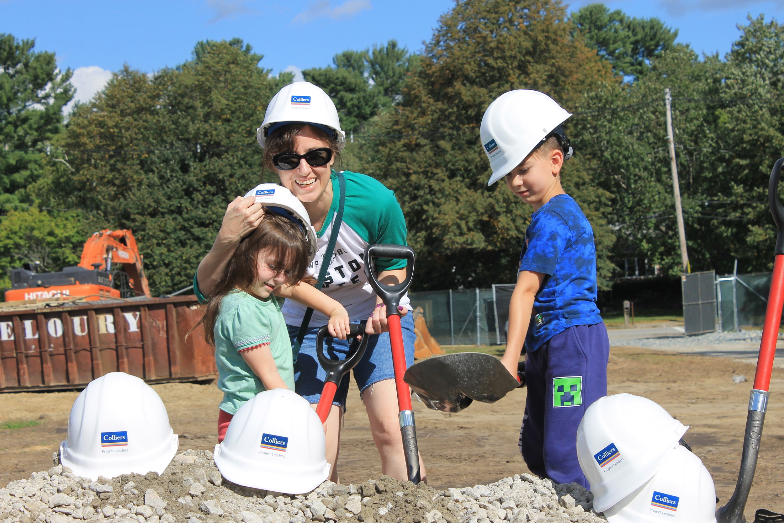 A family tries on hard hats and shovels at the Killam School groundbreaking site.