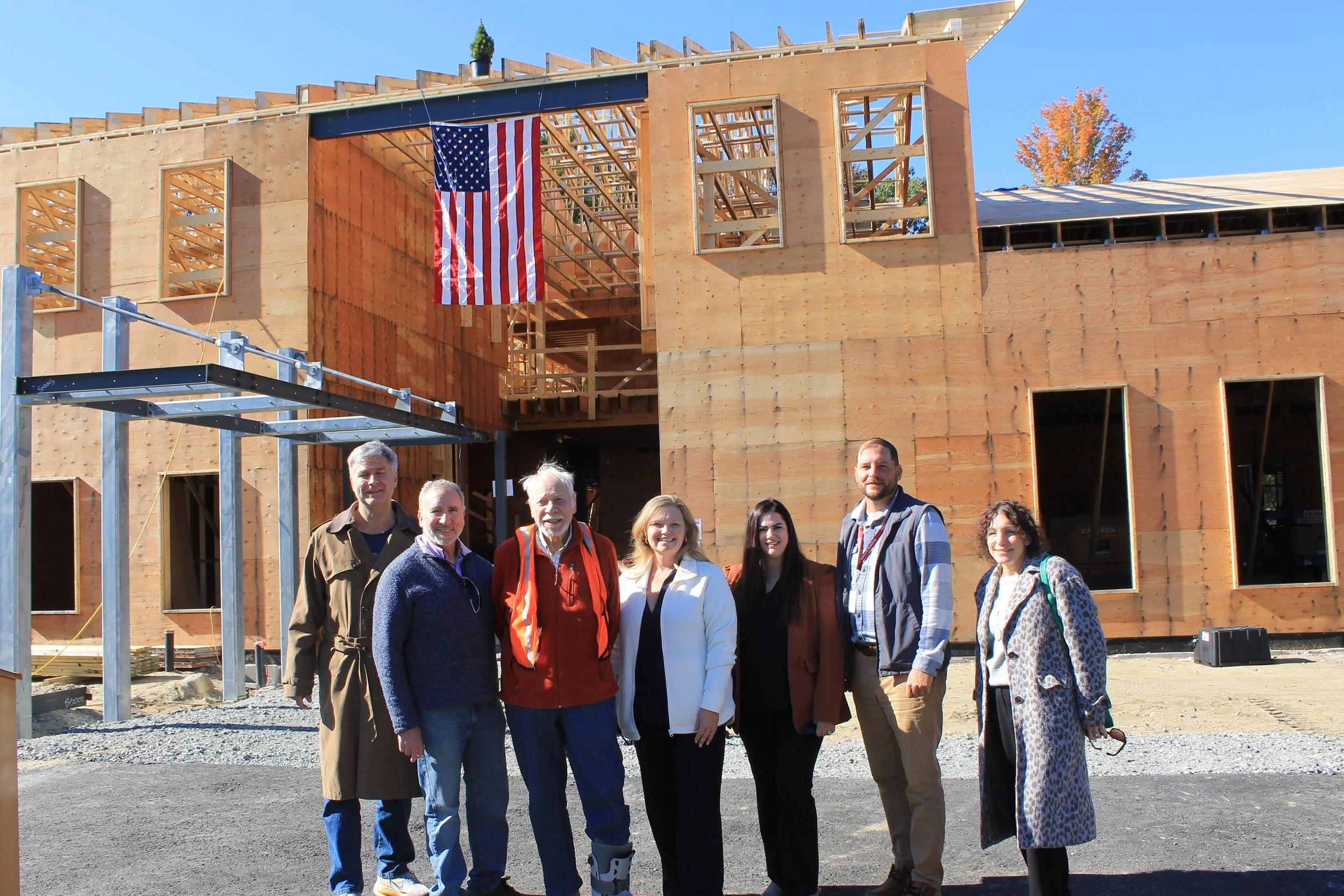Members of town staff and project volunteers gathers beneath the topped-off beam.