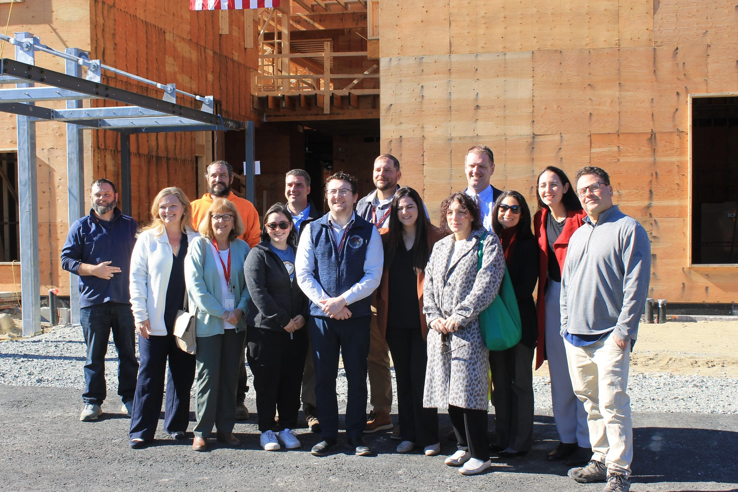 A larger group of town staff and project contractors pose for a photo in front of the ReCAL building.