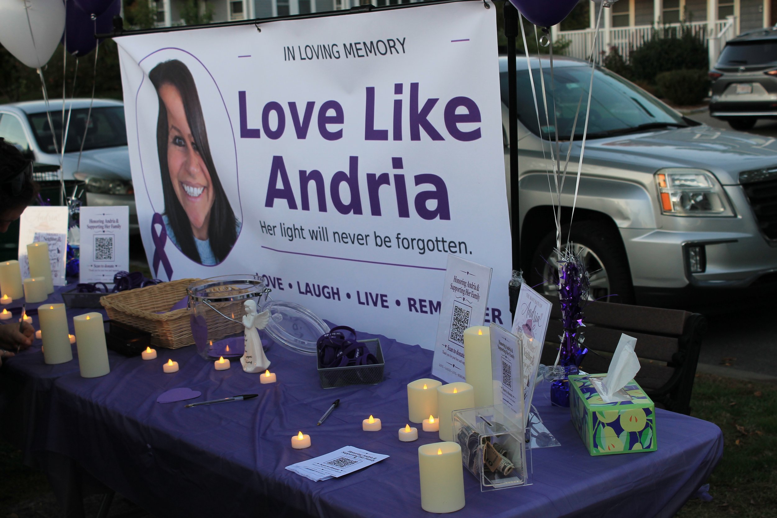 A banner reading "Love Like Andria, her light will never be fogotten" hangs above the memorial table.