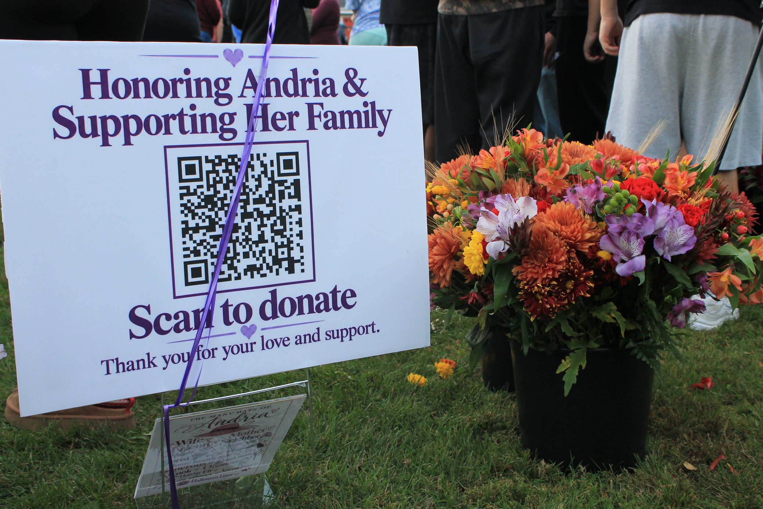 A sign next to the memorial table invites visitors to scan a QR code to support Andria's family.