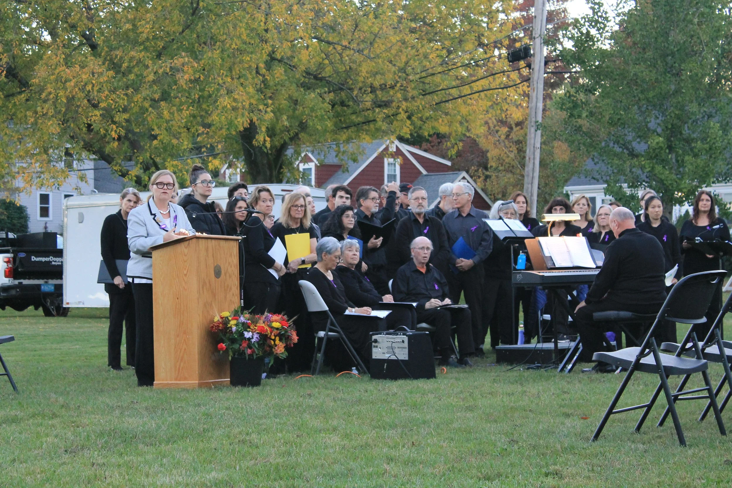 Town Manager Jayne Wellman addresses the crowd as the choir looks on.