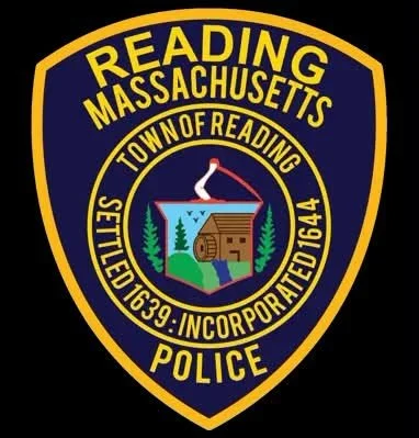 Official badge patch of the Reading, Massachusetts Police Department, featuring a mill scene with the town's settlement date of 1639 and incorporation date of 1664.