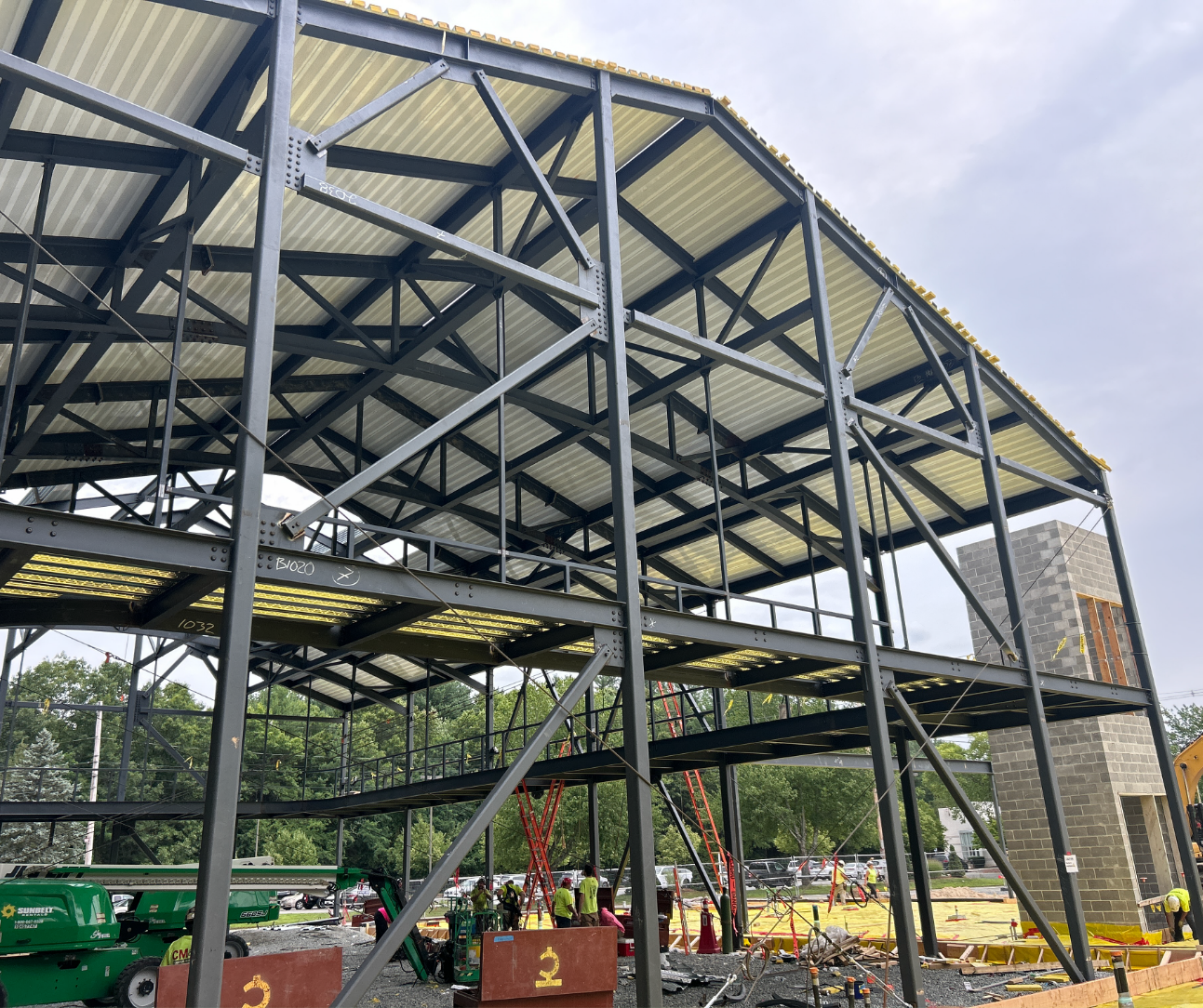 A view looking up at a steel building frame with metal roof decking installed overhead and diagonal bracing between the columns.