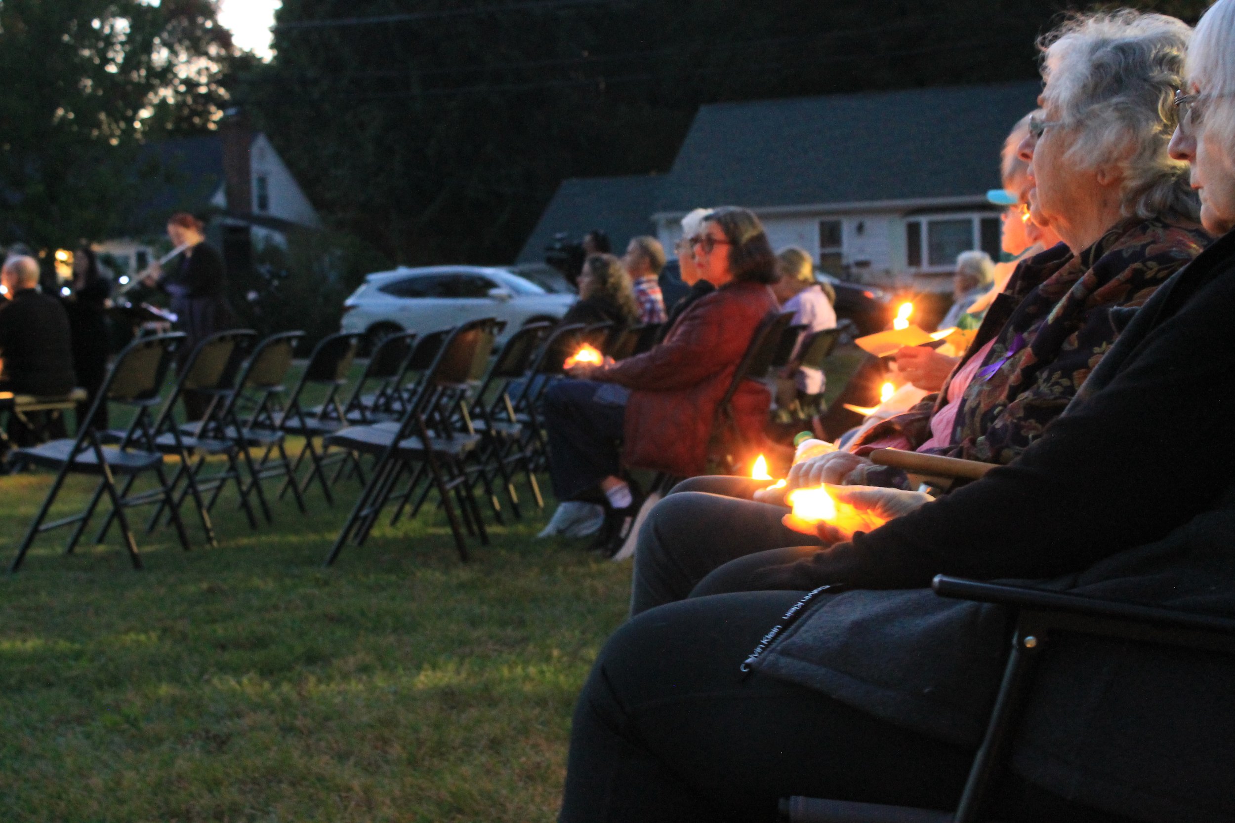 The Reading Community Singers, dressed in black, perform outdoors at dusk during the candlelight vigil for Andria Hanafin.
