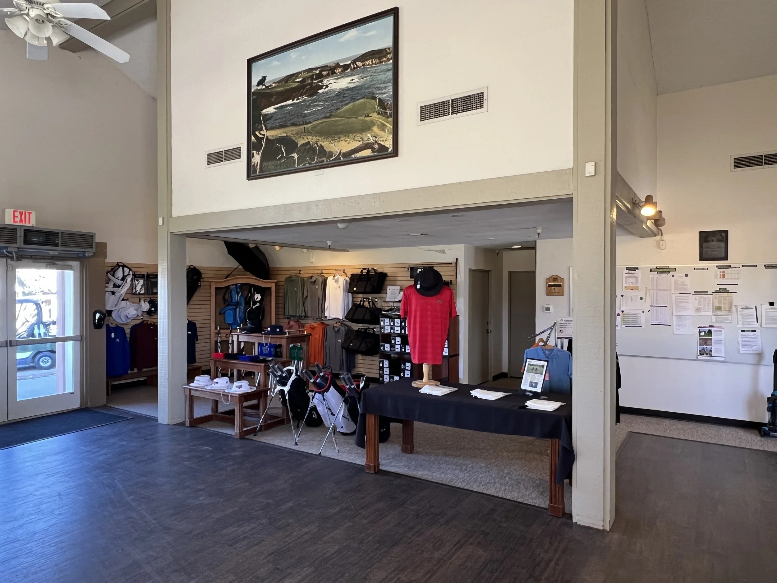 Interior of Seven Hills Golf Club pro shop with golf merchandise, a mannequin in a red shirt, and a display table.
