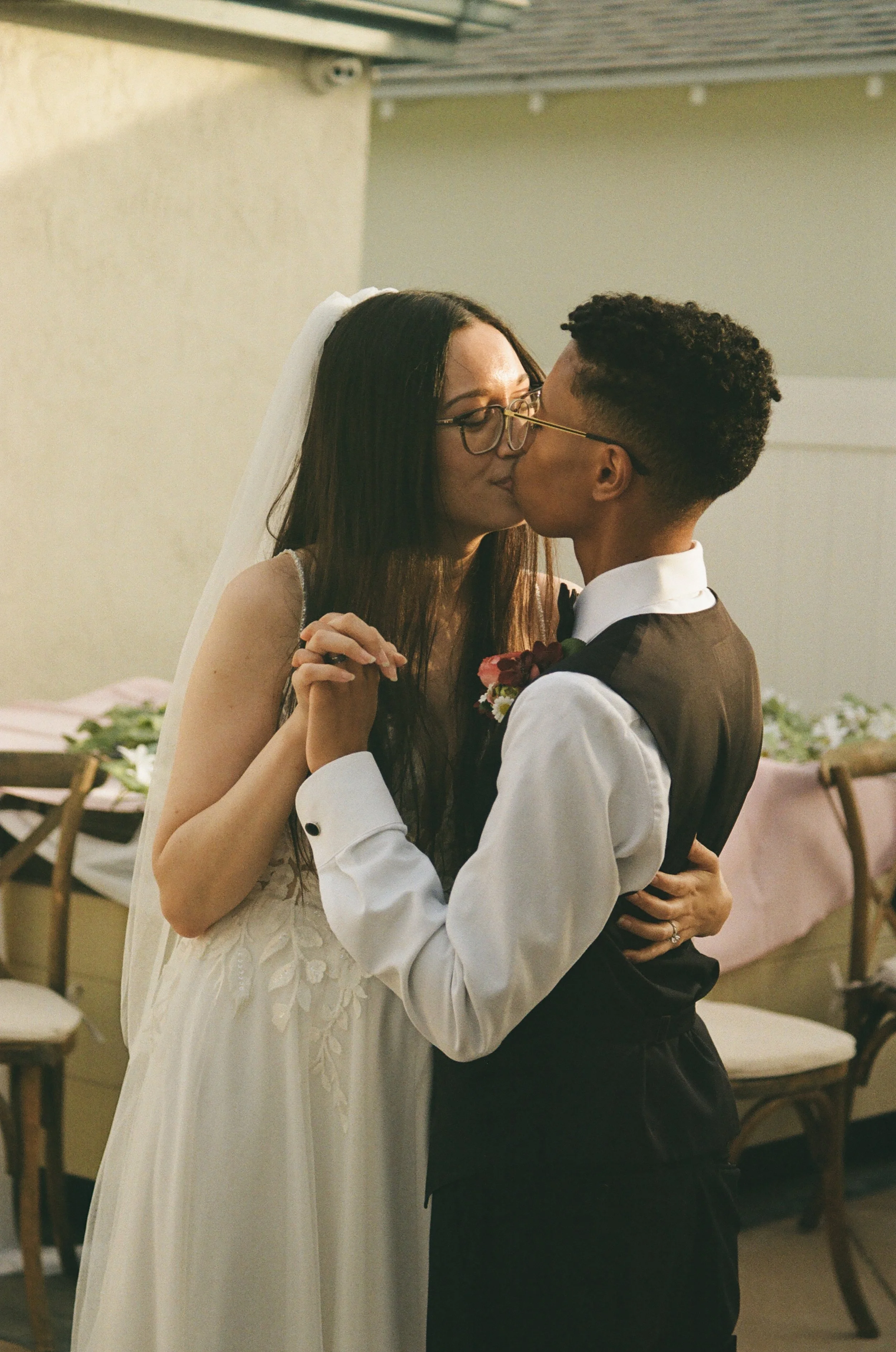 A bride and groom sharing a kiss during their wedding dance indoors.