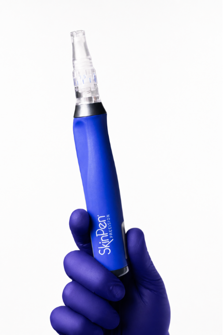 A hand wearing a purple glove holding a blue SkinPen Precision microneedling pen against a white background.