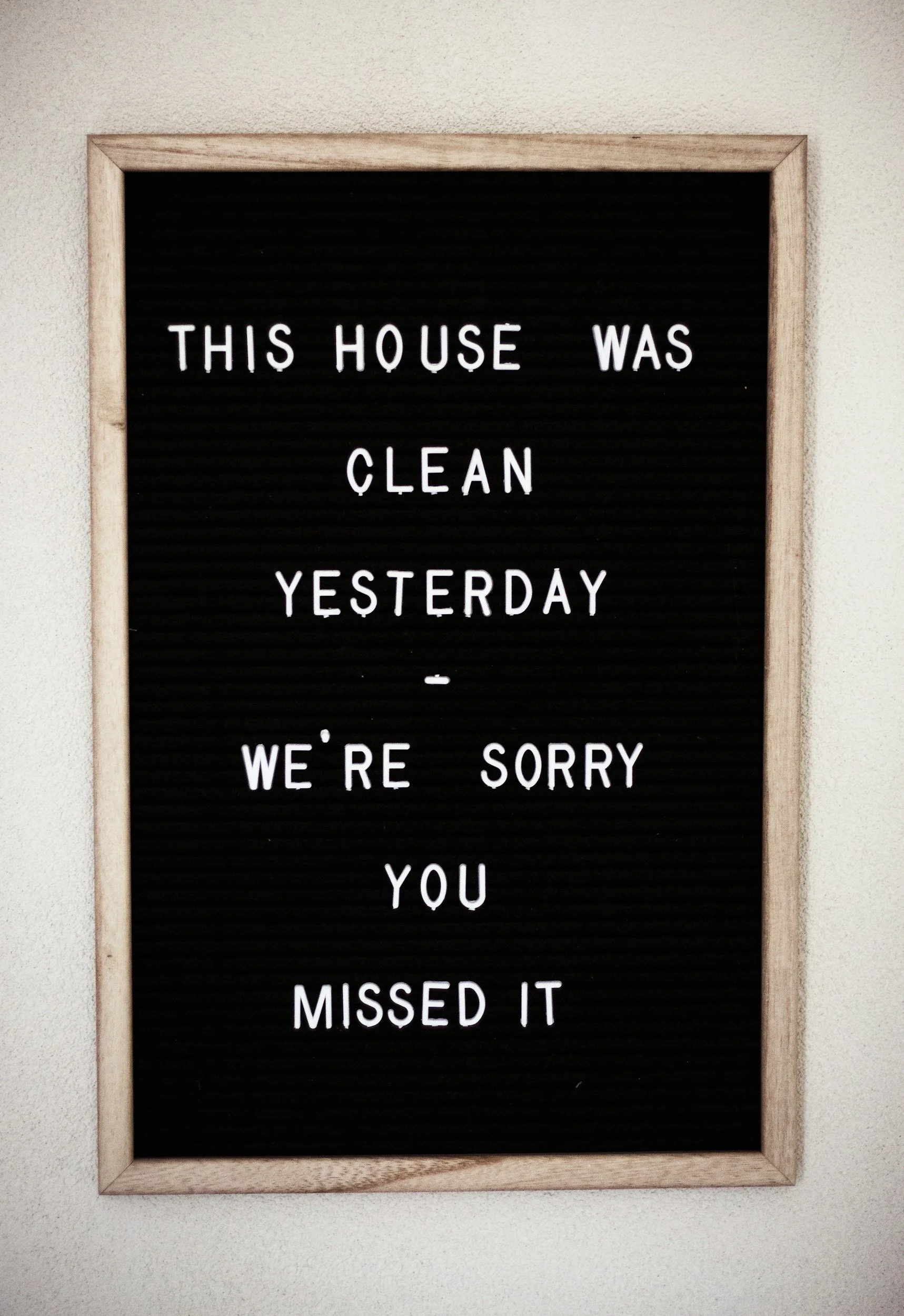 A black letter board with a wooden frame displaying the message, 'This house was clean yesterday - we're sorry you missed it.'