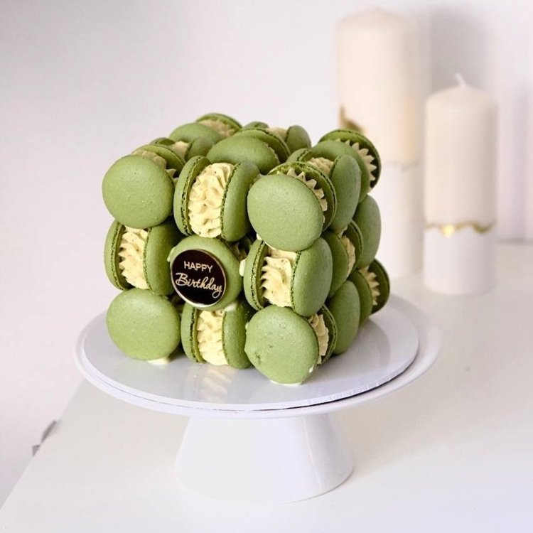 A cube of green macarons with a Happy Birthday topper