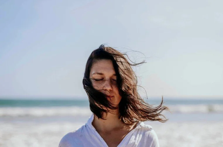 Woman in a beach while eyes closed - Orthodox Therapist