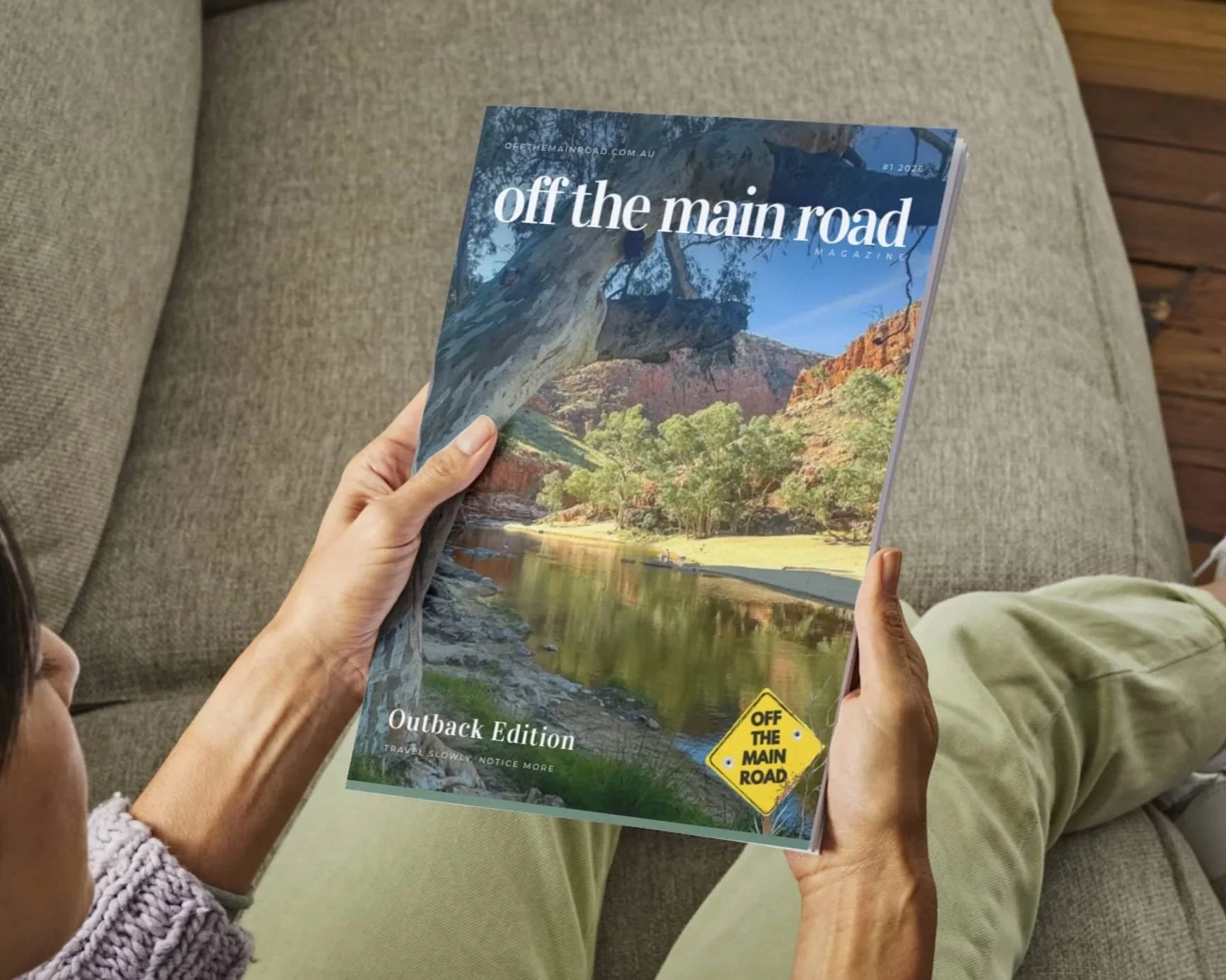 Person reading the Off the Main Road Magazine Outback Edition, showing the cover photo of Cameron Gorge