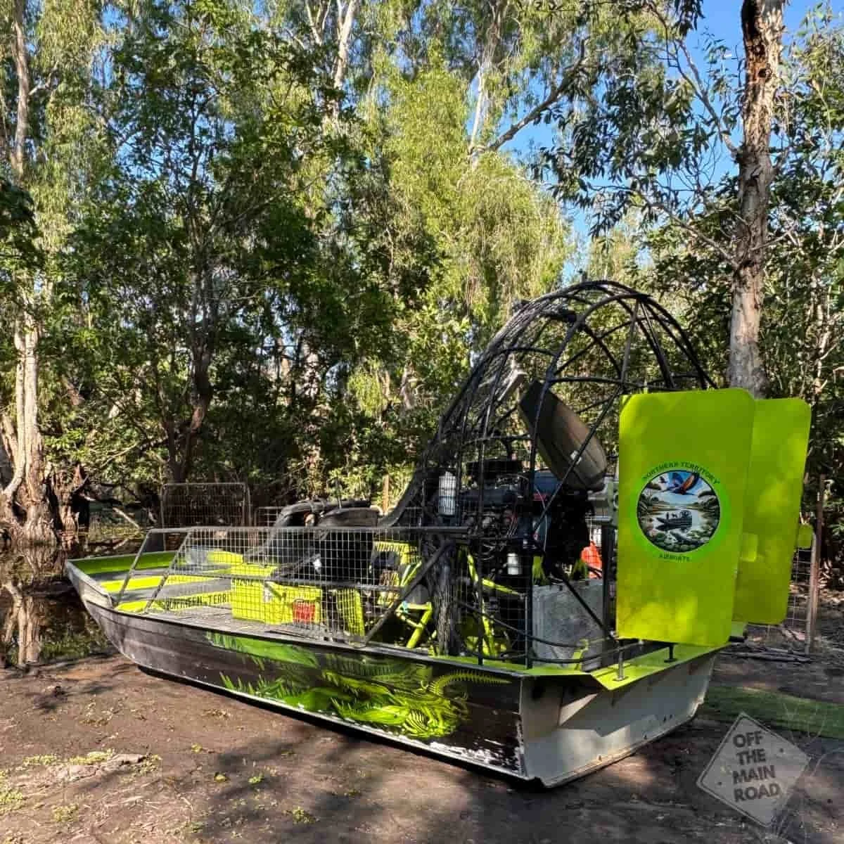 Northern Territory Airboats vessel moored on the banks of a billabong near Darwin, surrounded by river red gums