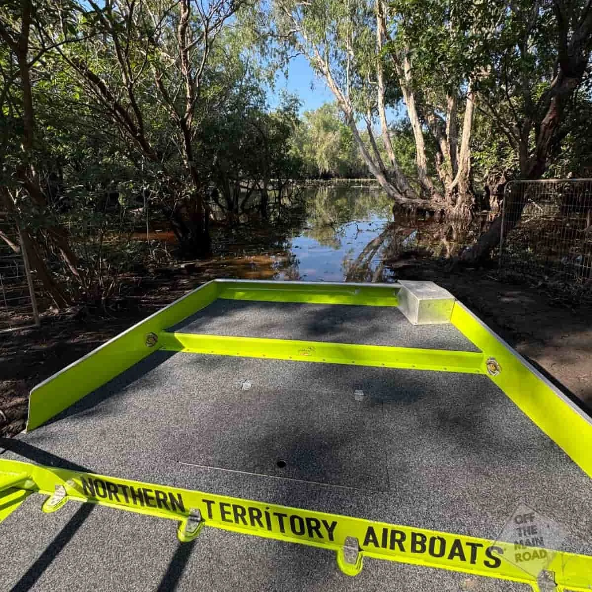 View from the front of a Northern Territory Airboats vessel gliding across a wetland channel, NT Airboats branding visible on the bow