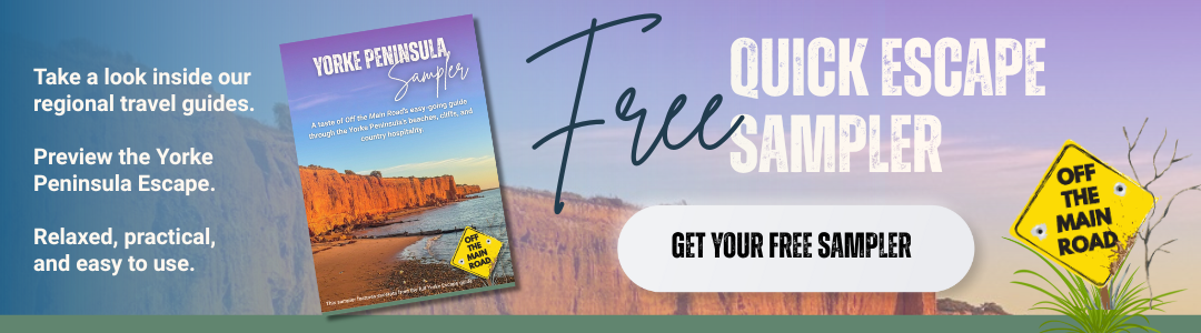A digital promotional banner for a regional travel guide to the Yorke Peninsula. It features a purple and blue gradient background with text advertising a free sampler guide. There is an image of the travel guide's cover showing a scenic coastline with cliffs and ocean. A yellow sign reading 'Off the Main Road' is on the right, next to a small plant. A call-to-action button says 'Get Your Free Sampler'.