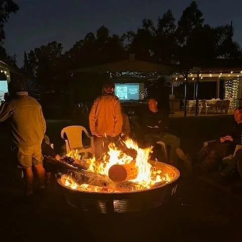 campfire and travellers gathered at a campsite under night sky