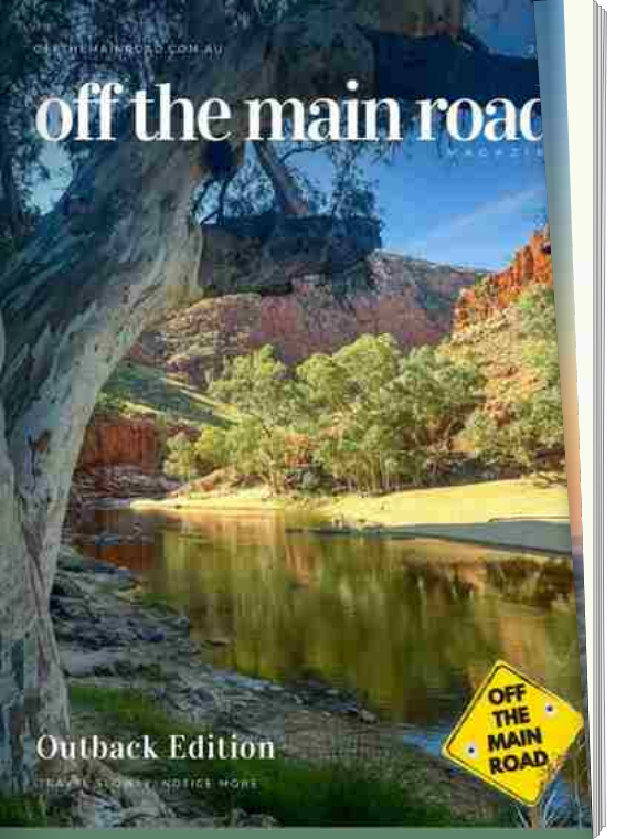 Cover of a Magazine titled 'Off the Main Road' with a scene of a river, trees, and red rock formations, and a yellow road sign with the words 'OFF THE MAIN ROAD' at the bottom right.