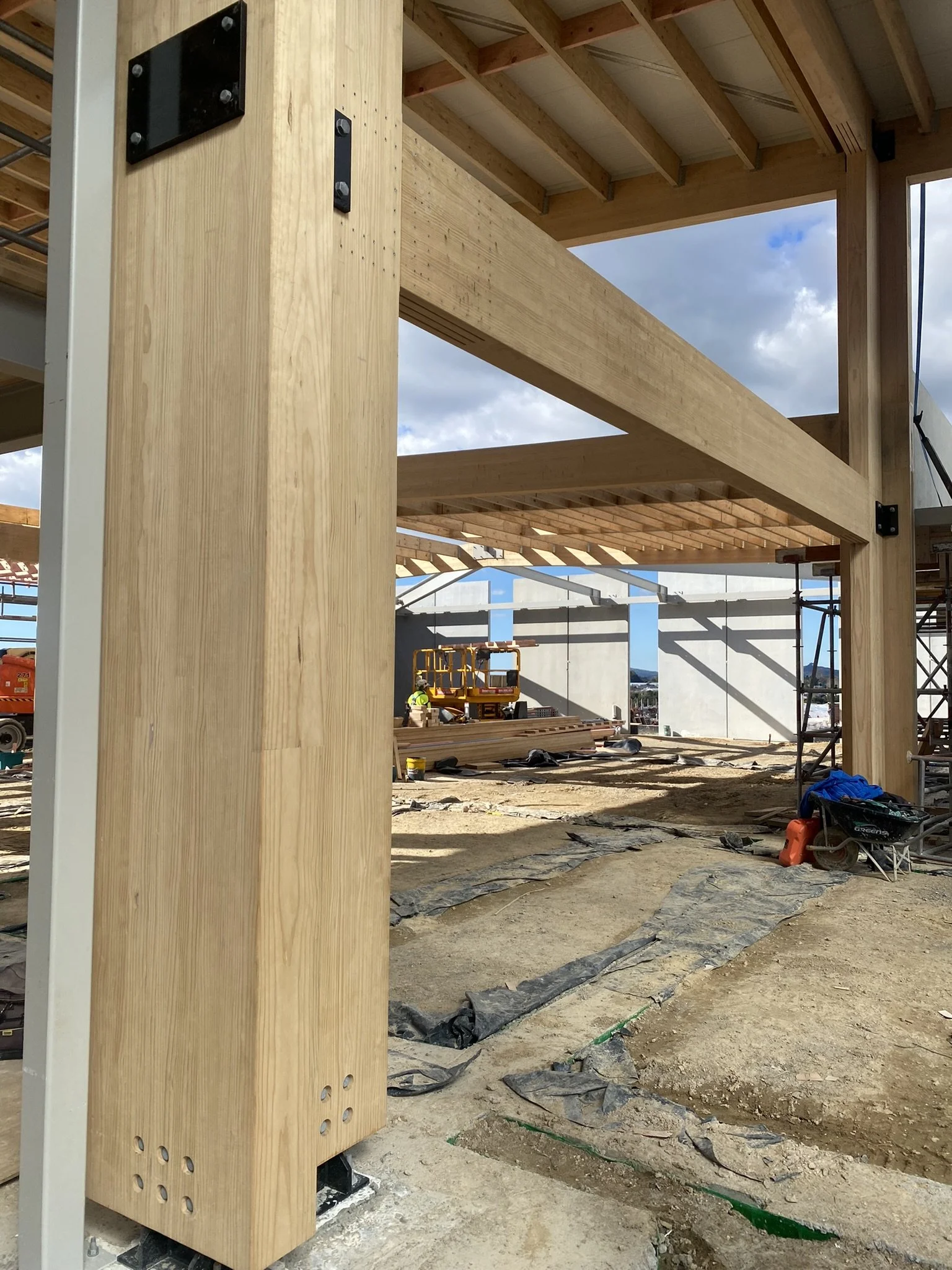 Construction site with wooden framework, construction workers, and tools, showing an ongoing building project outdoors.