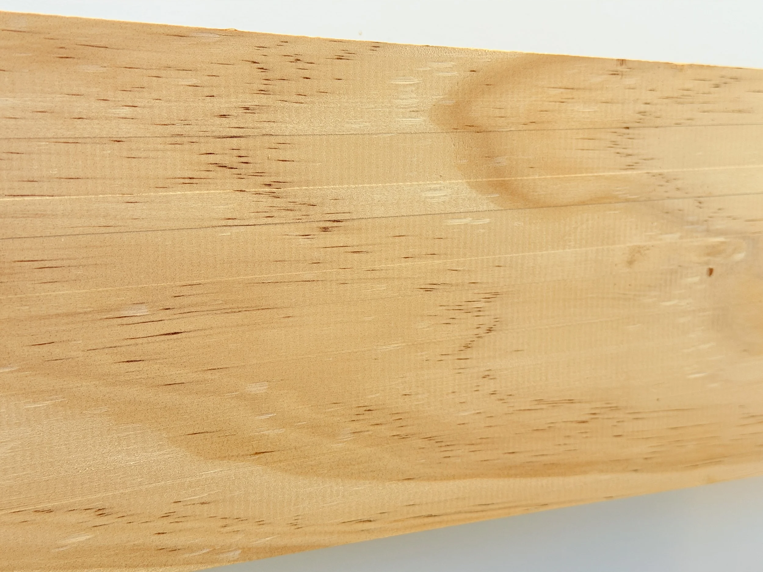 Close-up of a smooth, light-colored wooden surface with visible wood grain and texture.