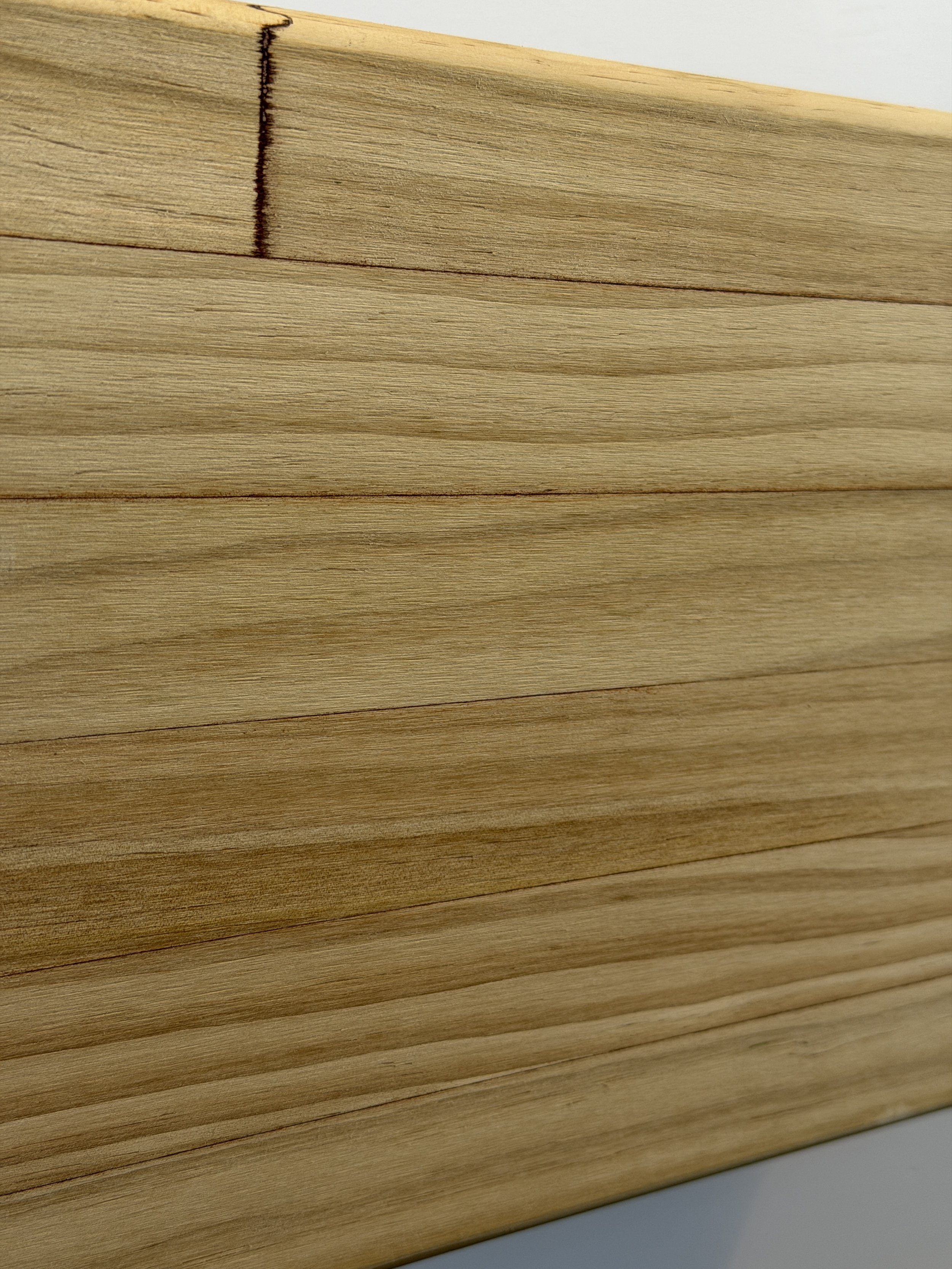 Close-up photo of a stack of light-colored wooden planks with a visible grain pattern.