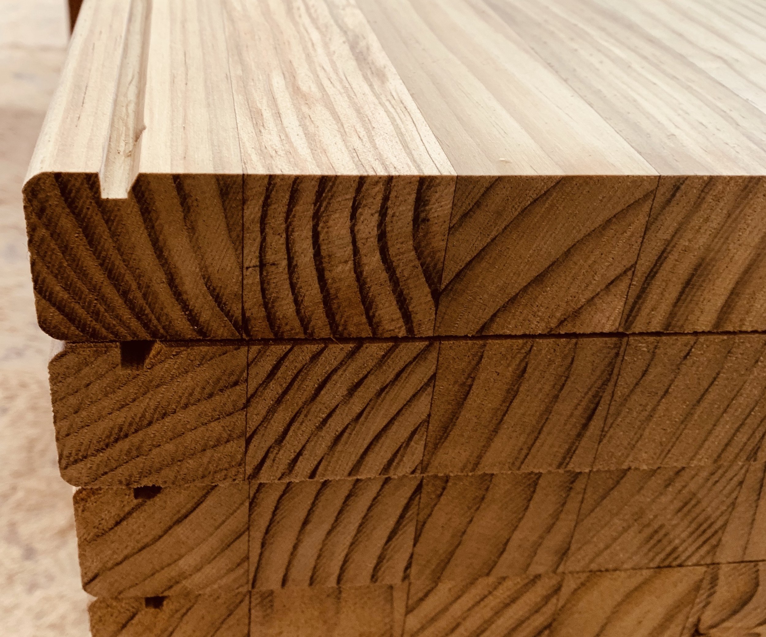 Stack of light-colored wooden planks with visible grain and texture.