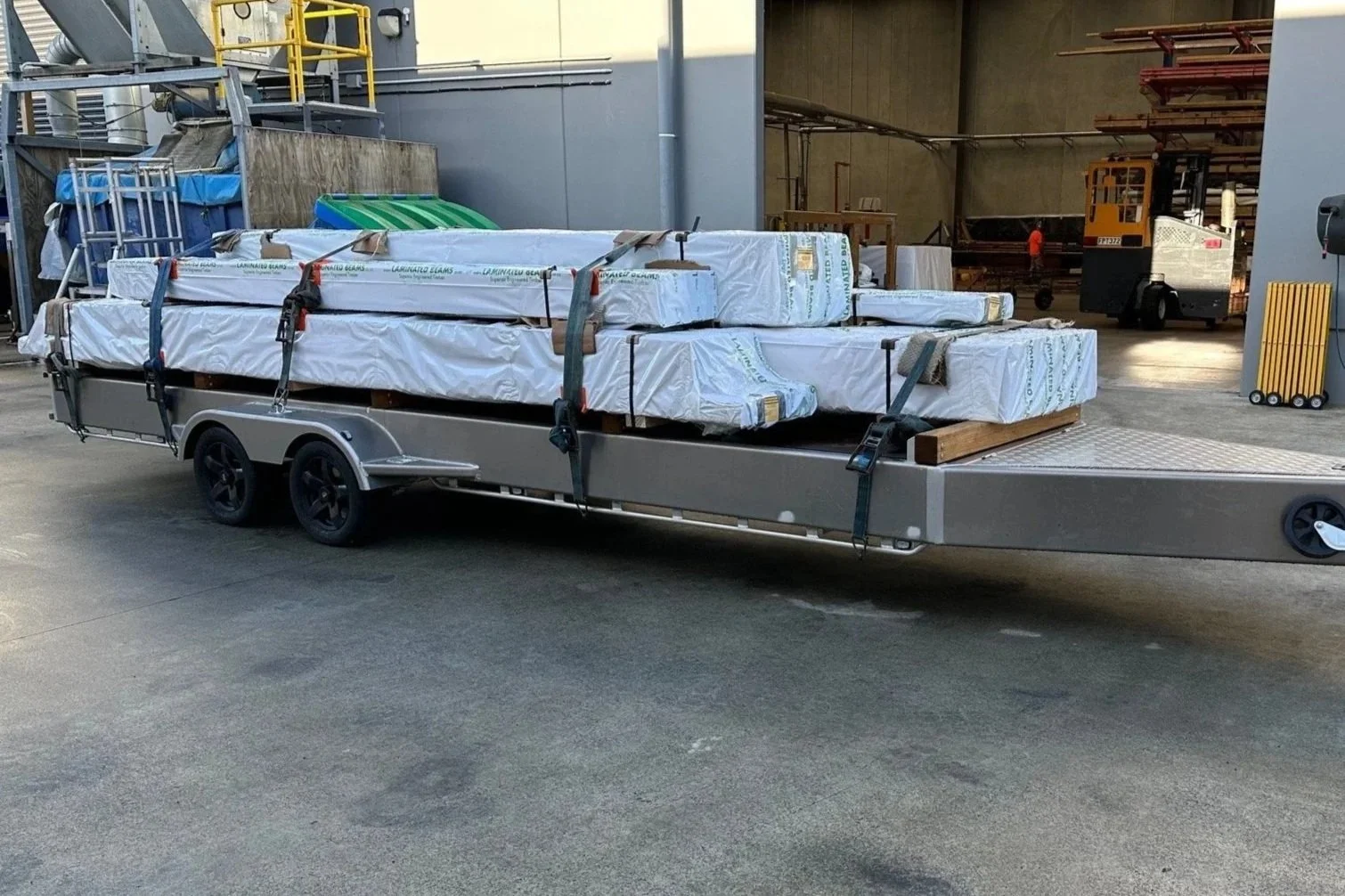 Glulam timber products wrapped and loaded on a trailer for delivery on site.
