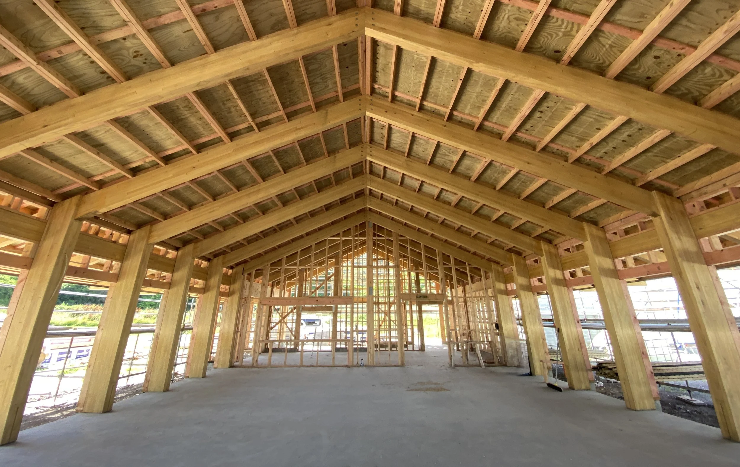 Construction site of a glulam timber marae building with exposed glulam beams and a vaulted ceiling.