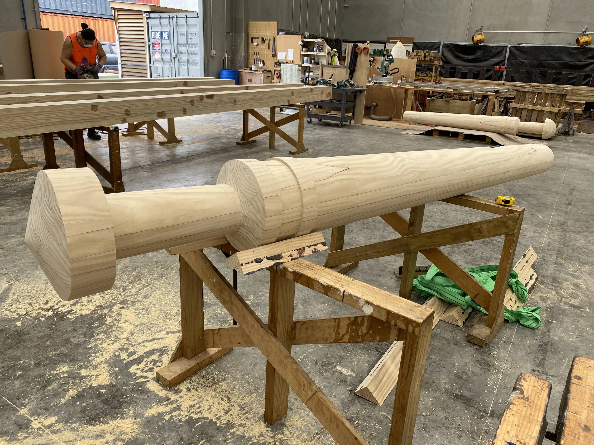 Laminated Beams factory workshop with large glulam timber pieces, tools, and workbenches.